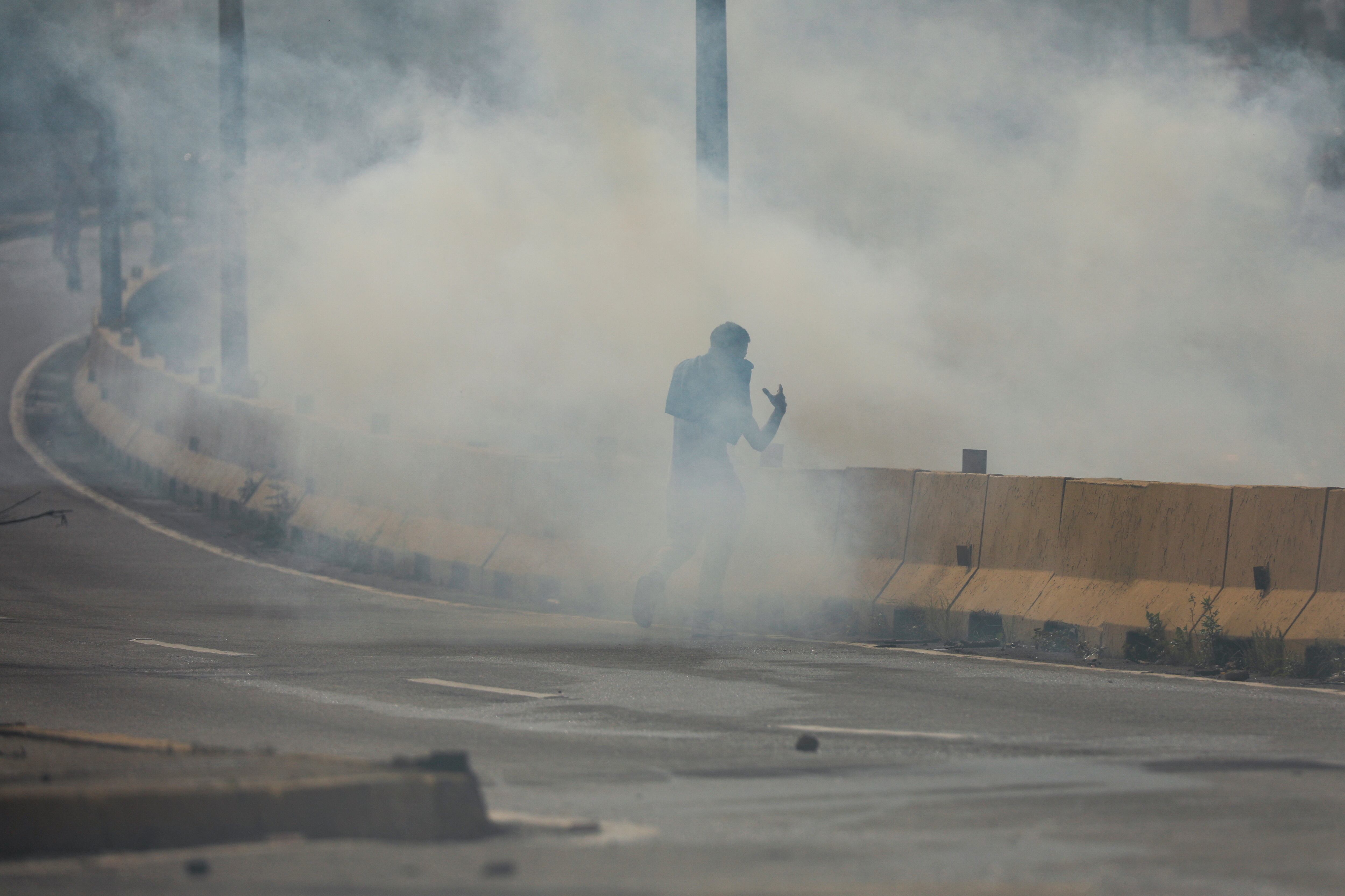 Un manifestante camina en medio de gases lacrimógenos durante los enfrentamientos con las fuerzas de seguridad en Caracas (REUTERS/Leonardo Fernández Viloria)