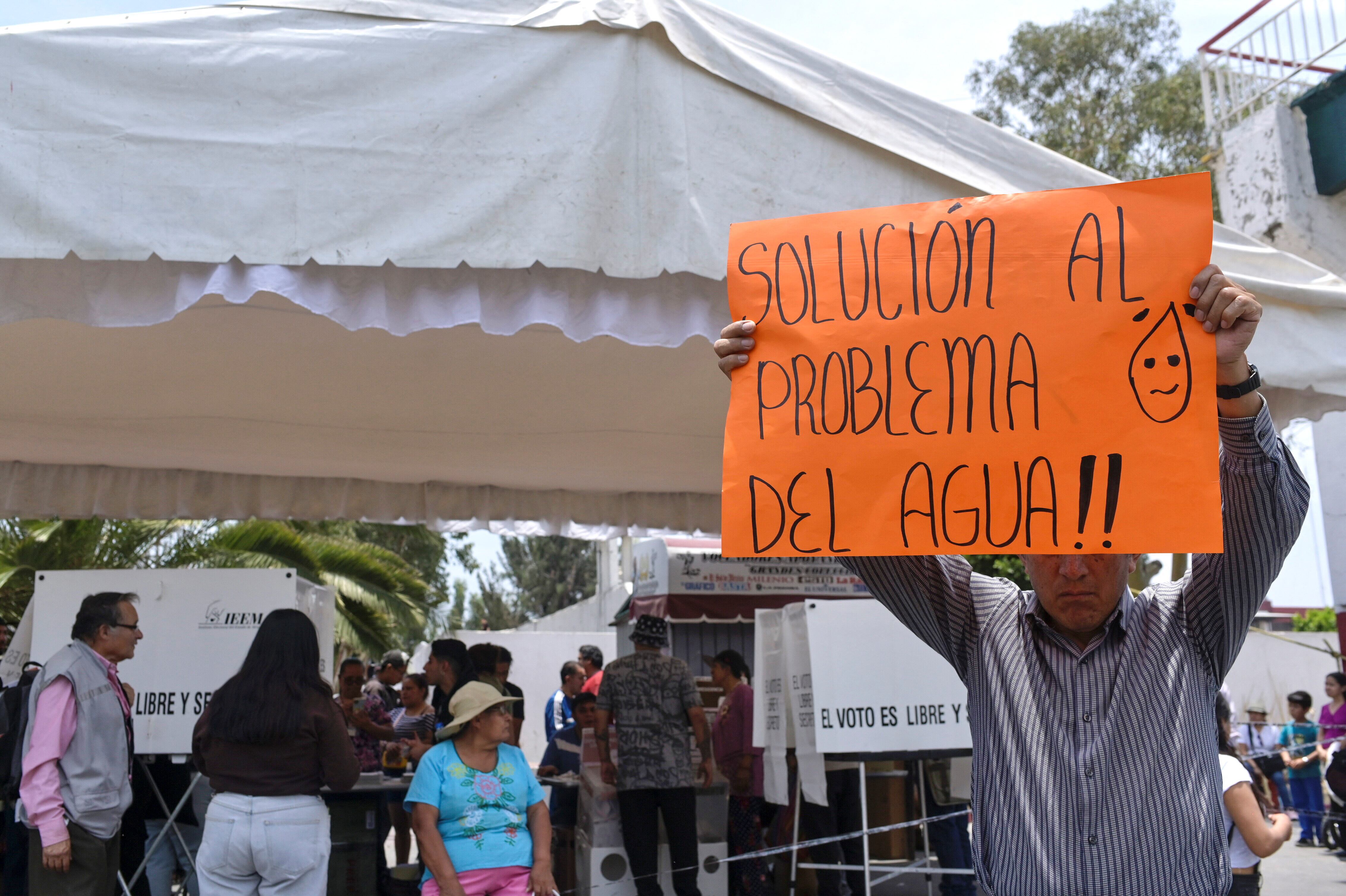 A man holds a banner as people protest over access to water outside a polling station, during the general elections, in Nezahualcoyotl, Mexico State, Mexico, June 2, 2024. REUTERS/Mahe Elipe