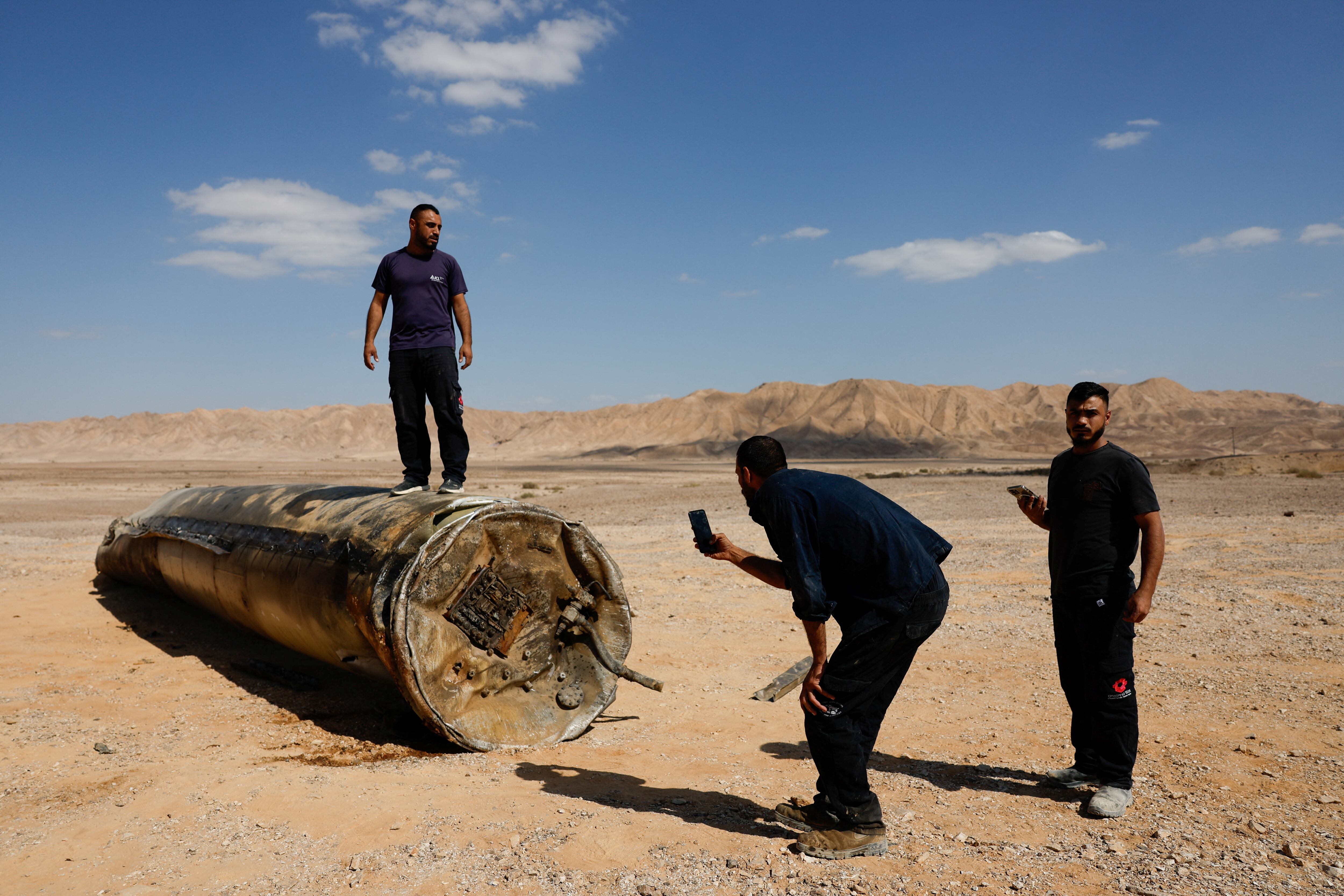 Un hombre se encuentra sobre los aparentes restos de un misil balístico que yacen en el desierto, luego de un ataque de Irán contra Israel