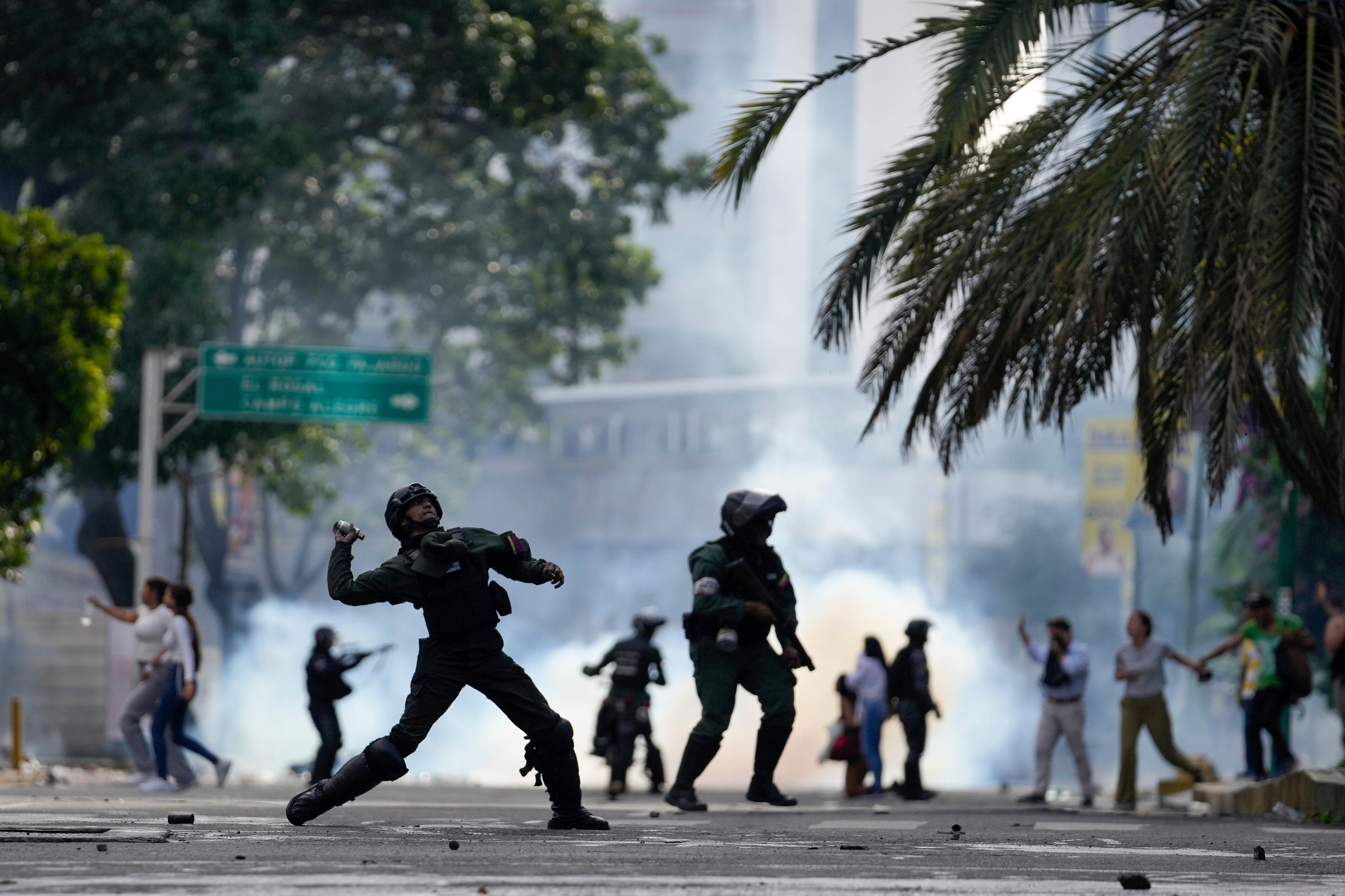 Un agente de policía lanza gases lacrimógenos contra manifestantes que protestan por los resultados electorales que declararon a Nicolas Maduro vencedor en las elecciones presidenciales de Venezuela, un día después de los comicios, en Caracas (AP Foto/Matías Delacroix)