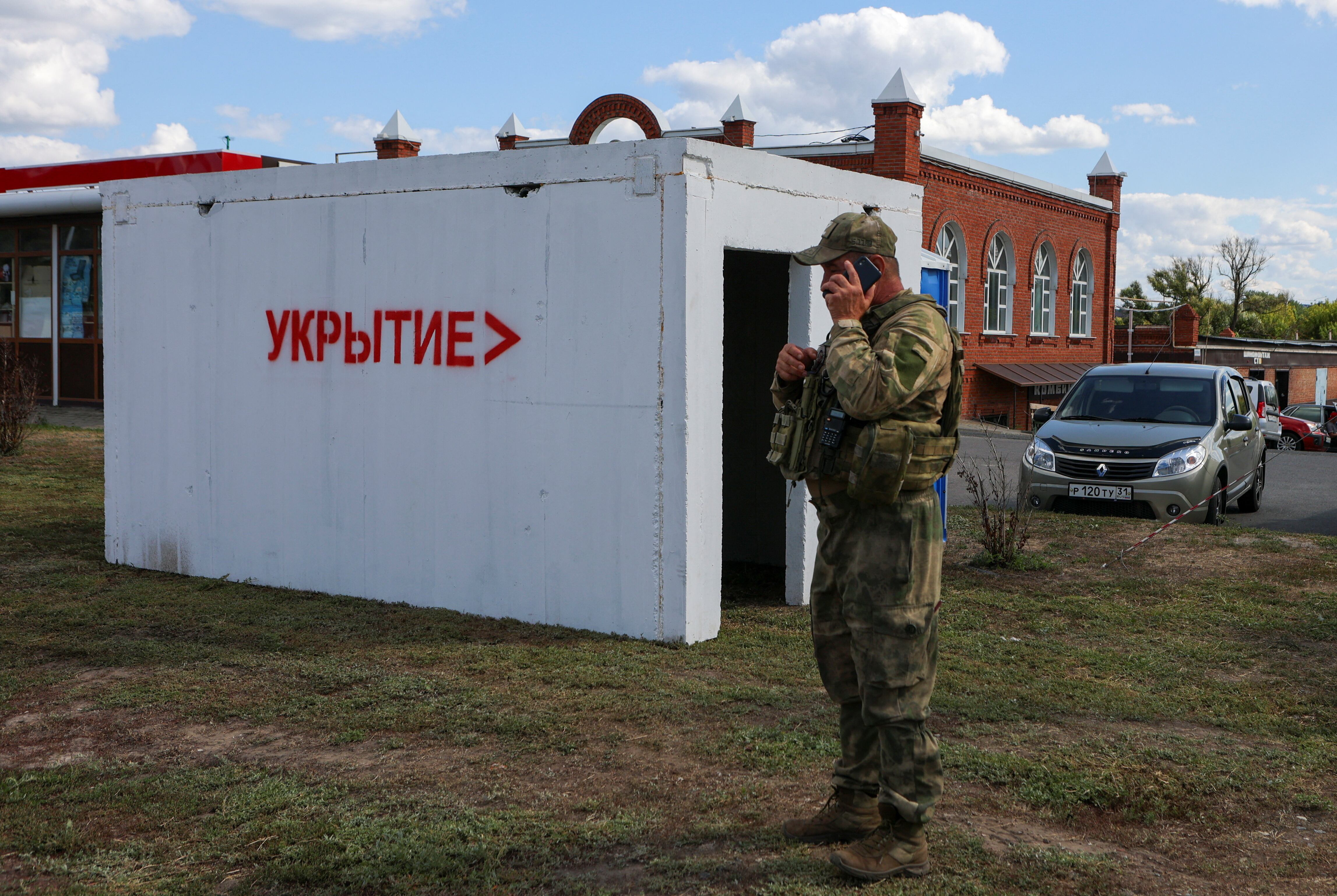 Un  militar habla por teléfono junto a un refugio antiaéreo en un puesto de control en las afueras en Belgorod. Un cartel en la construcción reza: "Refugio (antibombas)". (REUTERS)