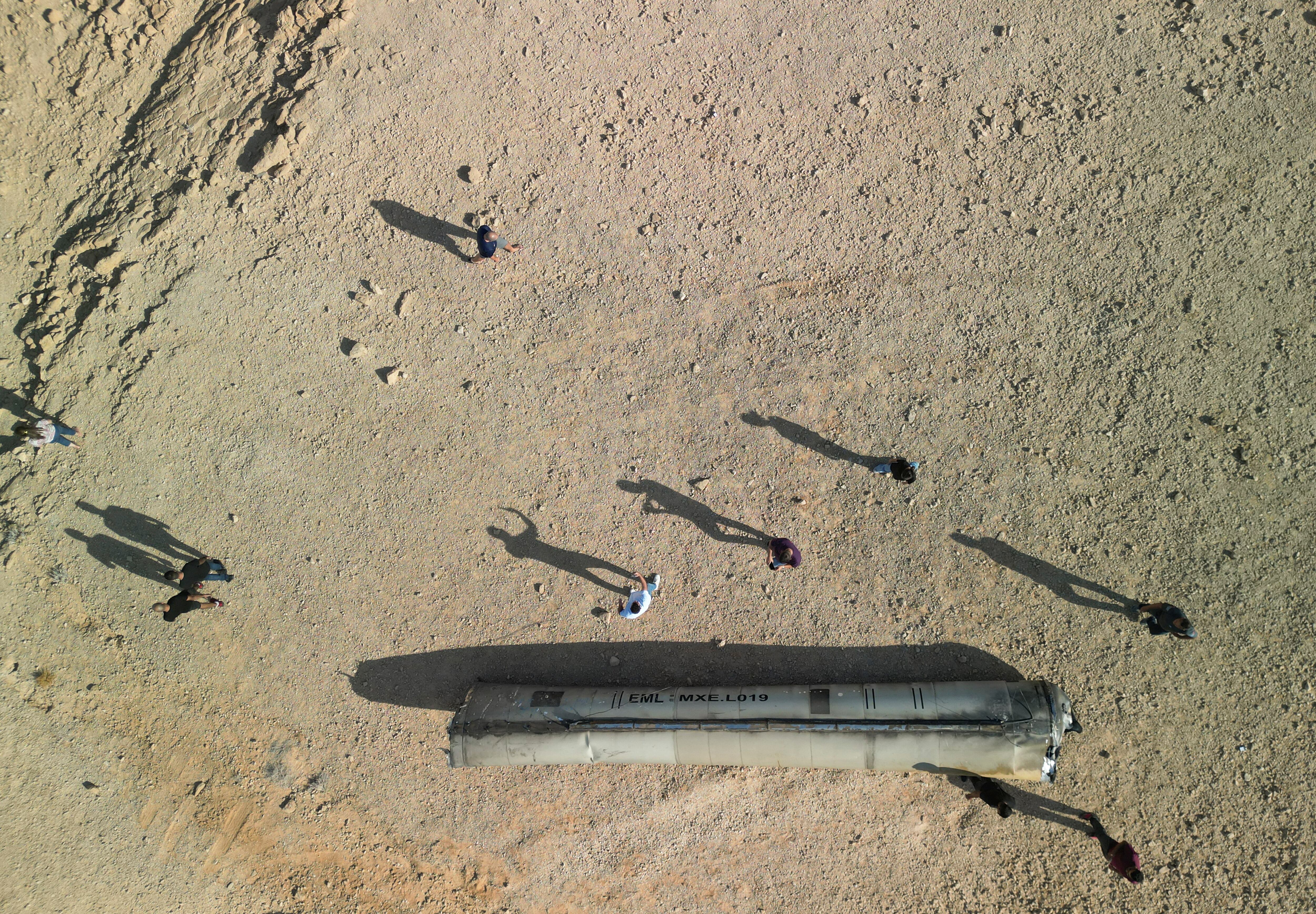 Una vista de un dron muestra a personas paradas alrededor de los aparentes restos de un misil balístico que yacen cerca de la ciudad sureña de Arad, Israel