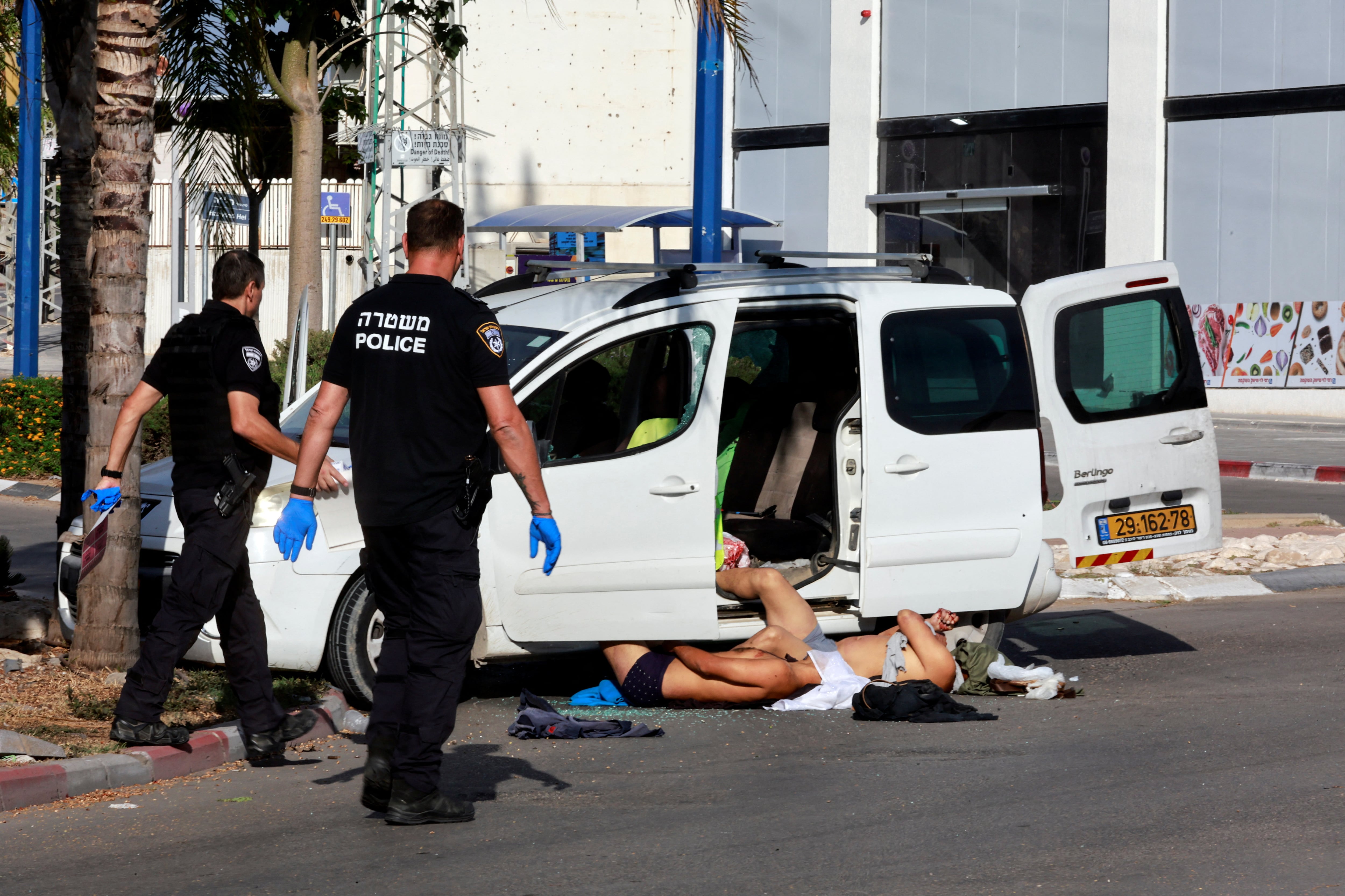 La policía israelí se acerca a los cuerpos de dos hombres que murieron en el ataque terrorista palestino en Sderot
