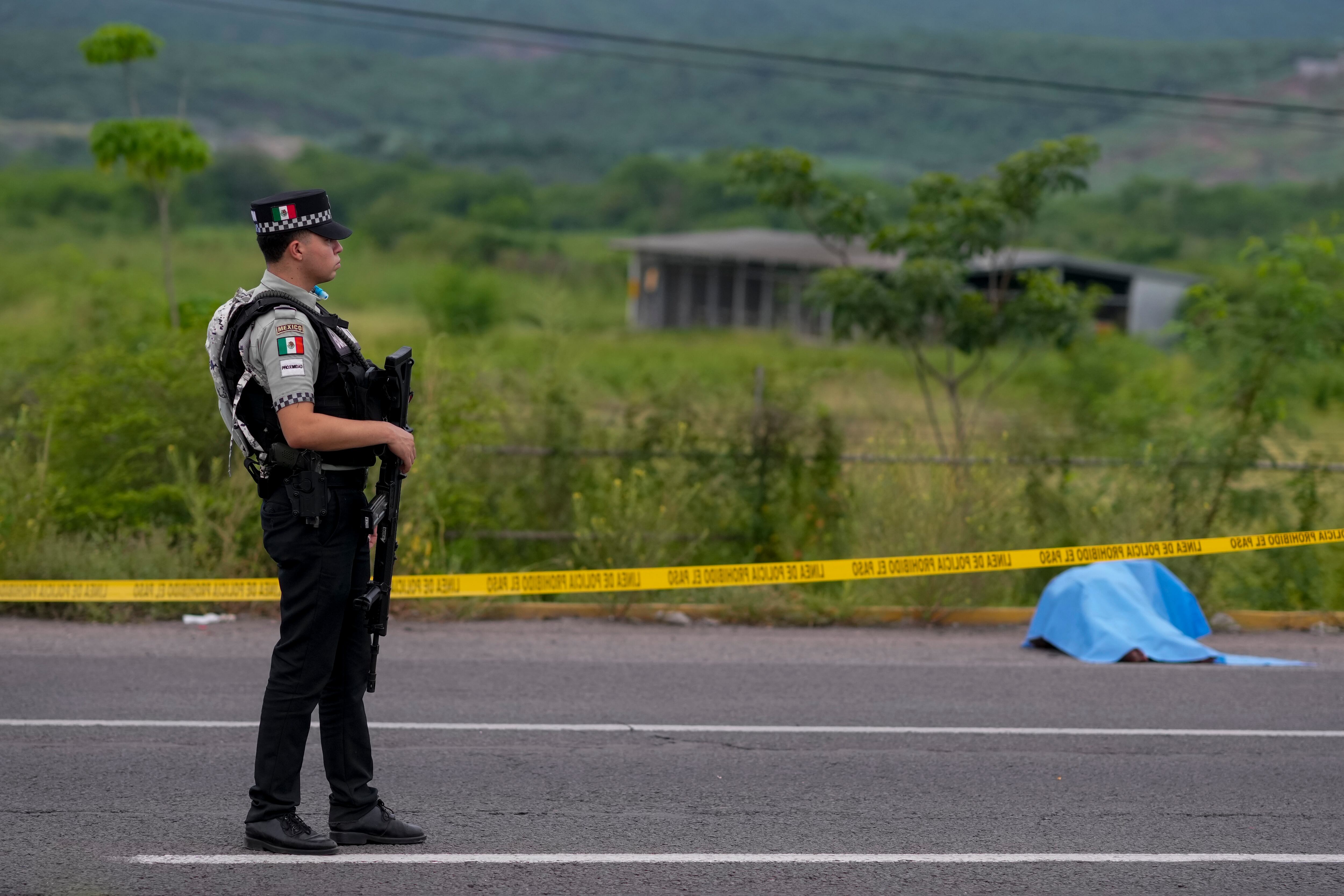 Un elemento de la Guardia Nacional Mexicana vigila junto a un cuerpo encontrado tirado a un lado de una carretera en Culiacán, estado de Sinaloa, México, el sábado 21 de septiembre de 2024. (AP Foto/Eduardo Verdugo)