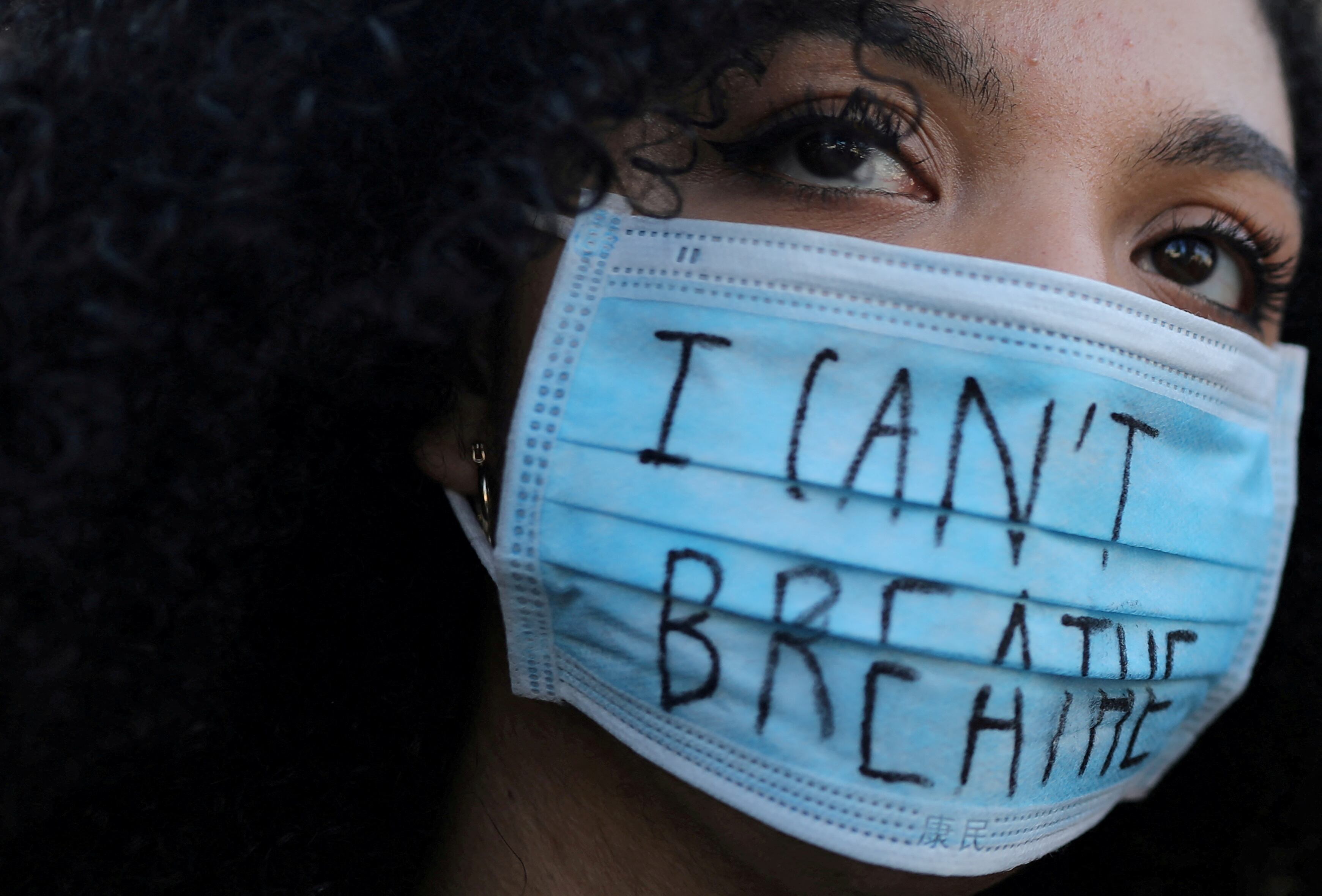 FILE PHOTO: A woman wearing a face mask with the words "I can't breathe" looks on during a protest against the death in Minneapolis police custody of George Floyd, in front of a U.S. consulate in Barcelona, Spain, June 1, 2020. REUTERS/Nacho Doce/File Photo