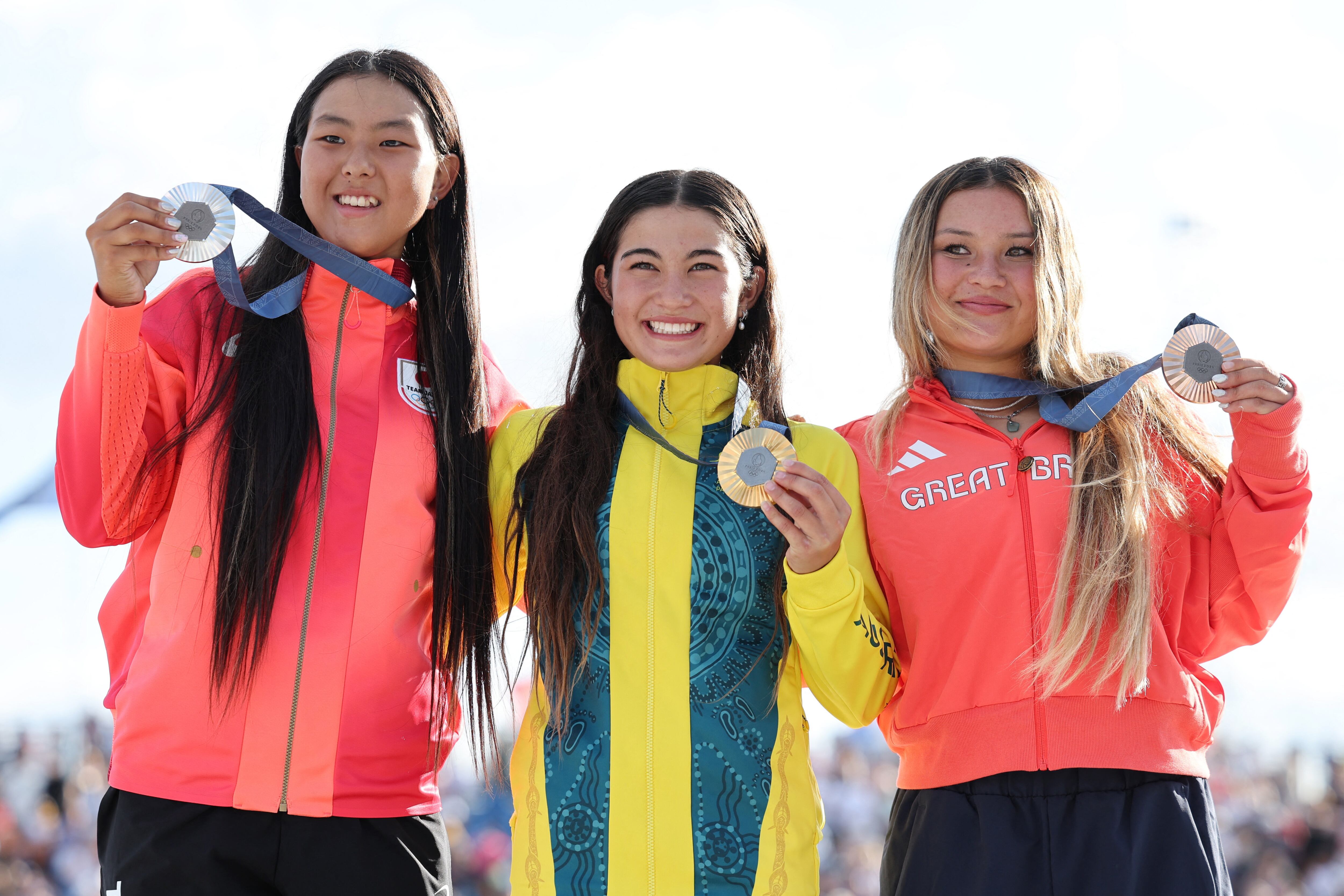 Podio juvenil en París 2024. La australiana Arisa Trew (14 años) ganó la medalla de oro y celebra en el podio junto con la japonesa Cocona Hiraki, medalla de plata, y la británica Sky Brown, medalla de bronce en la Concorde (REUTERS/Mike Blake)