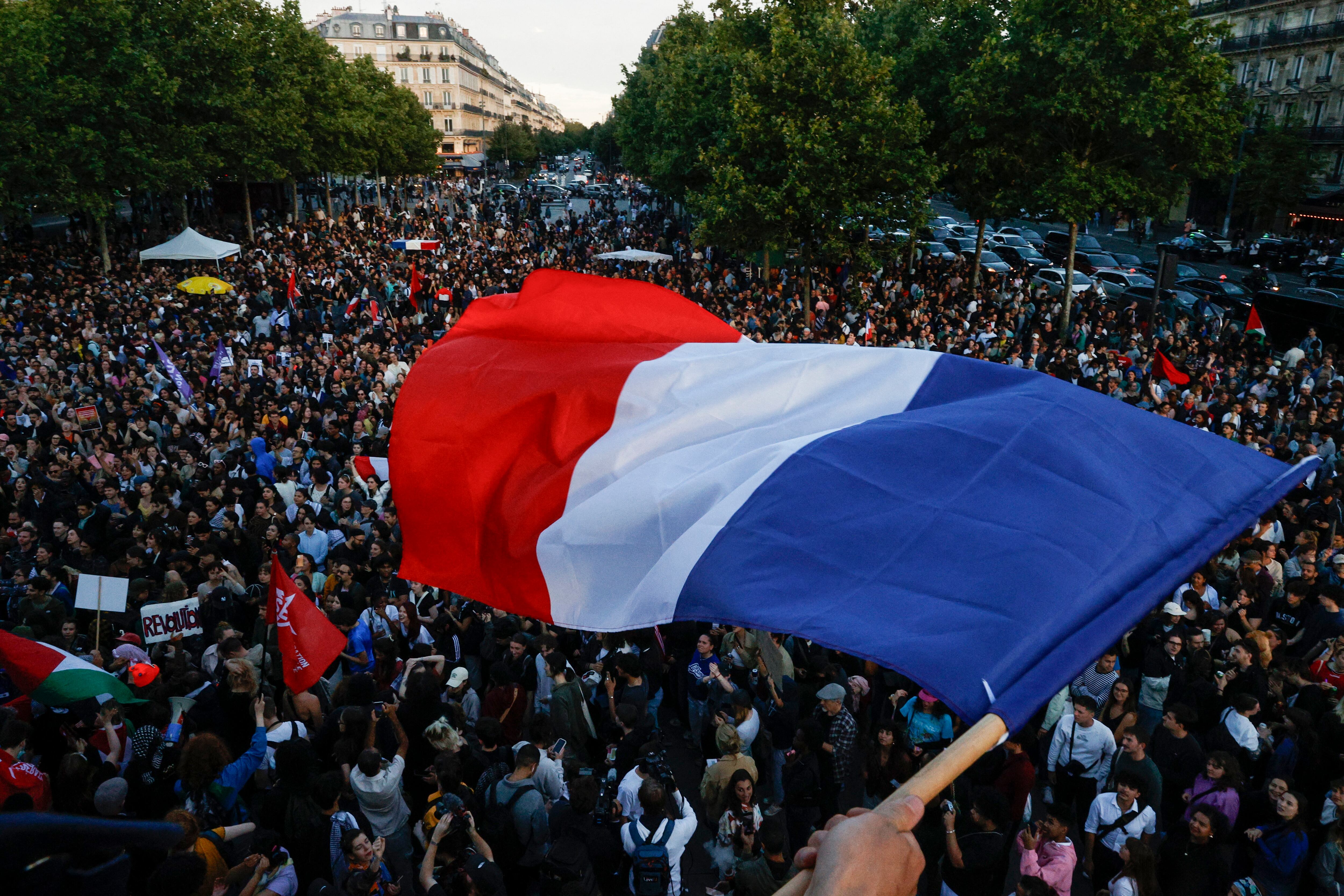 Un manifestante ondea una bandera francesa ante la concentración en la Plaza de La República este domingo, tras conocer los resultados parciales de la segunda vuelta de las legislativas (REUTERS/Abdul Saboor)