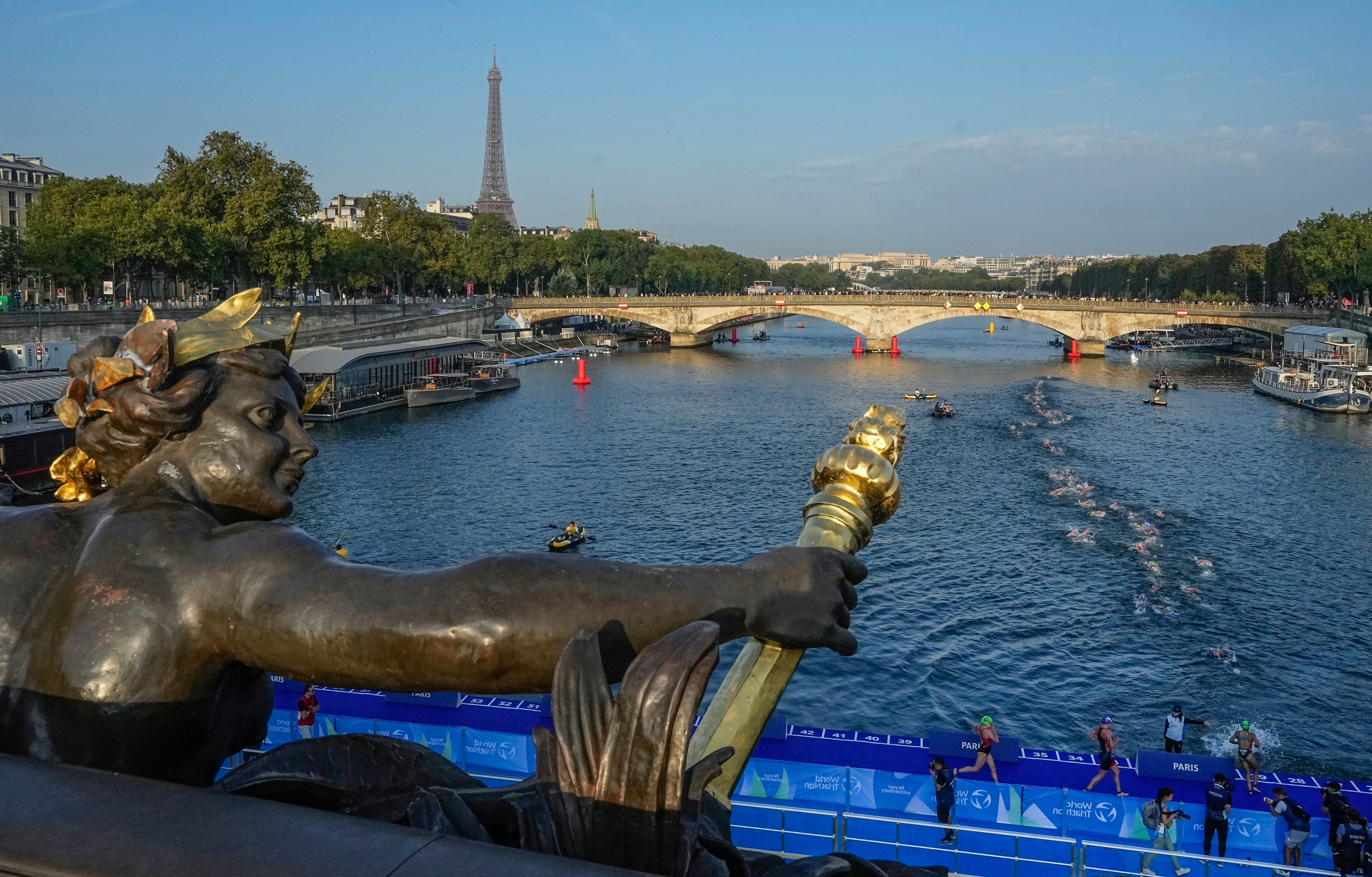 Triatletas compiten en el río Sena durante una prueba femenina previo a los Juegos Olímpicos de París (AP Foto/Michel Euler)