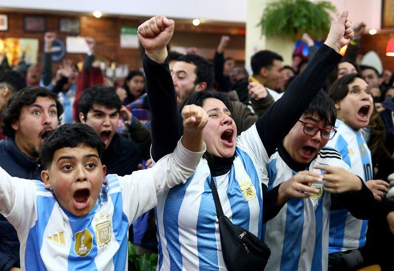 Con los brazos en alto y la camiseta, los hinchas argentinos en pleno festejo tras el final del partido 