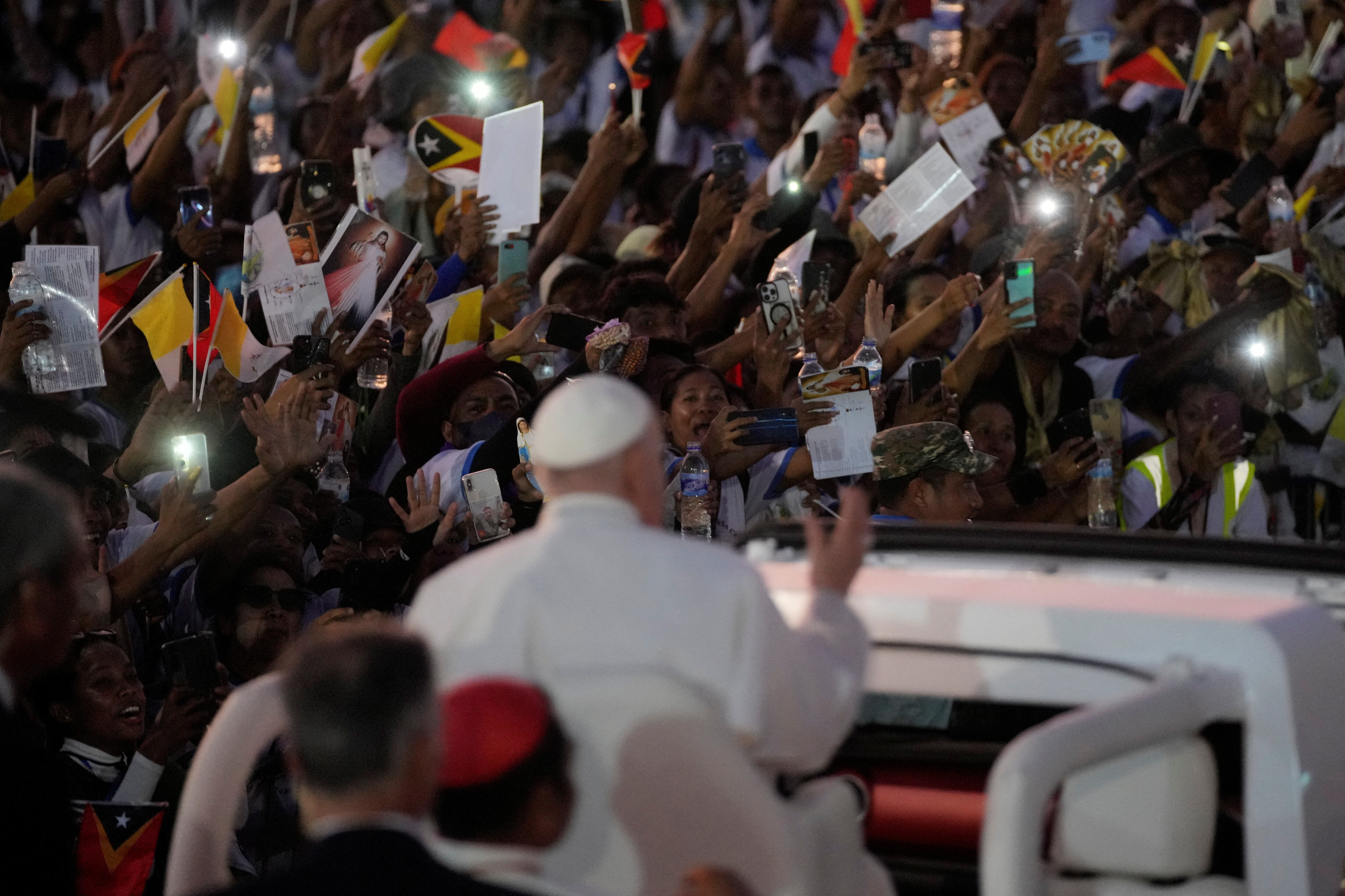 Un grupo de personas saluda al Papa Francisco a su salida tras oficiar una santa misa en el parque Tasitolu de Dili, Timor Oriental.