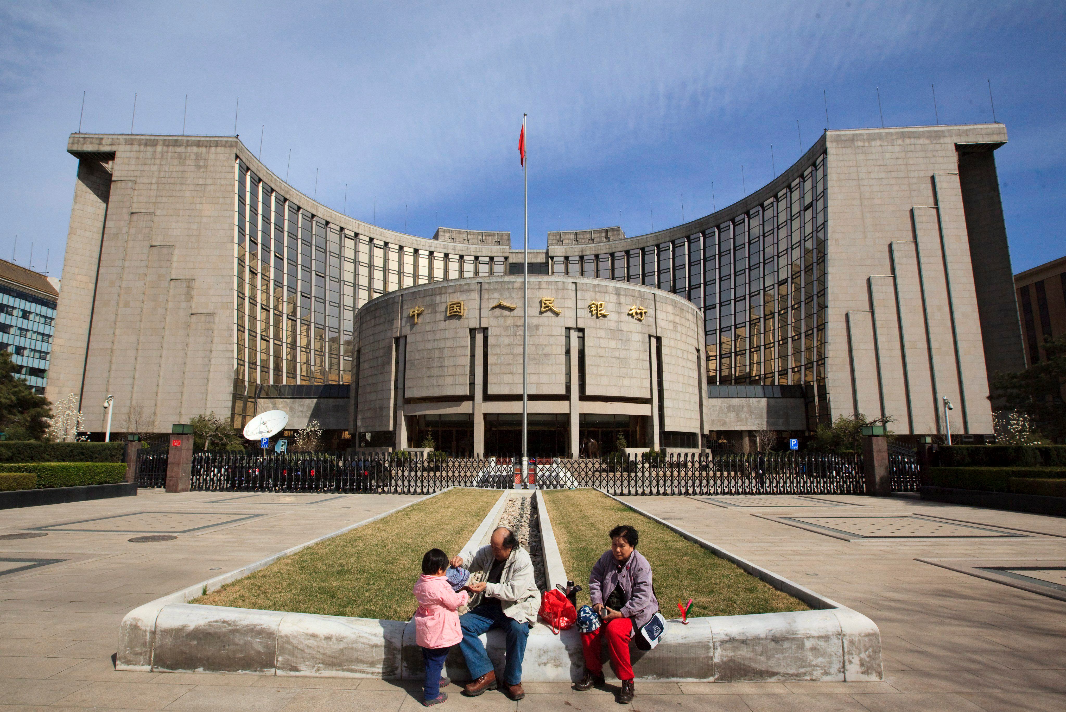 Una familia descansa delante de la sede del Banco Popular de China (Banco Central, BPC) en Beijing (EFE/Adrian Bradshaw/Archivo)