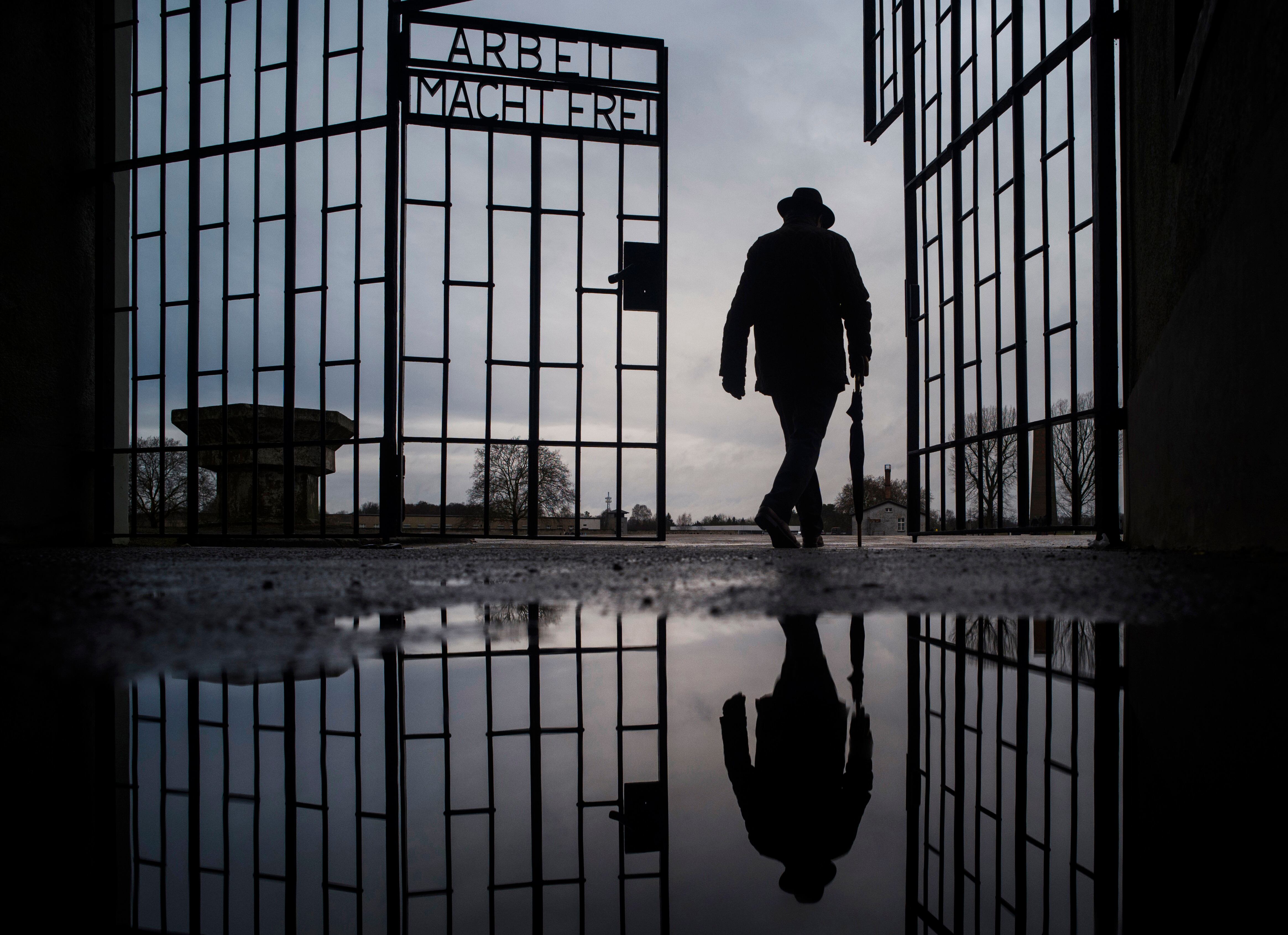 Un hombre cruza la puerta del campo de exterminio nazi de Sachsenhausen, en la que dice en alemán "El trabajo os hará libres". (AP Foto/Markus Schreiber)