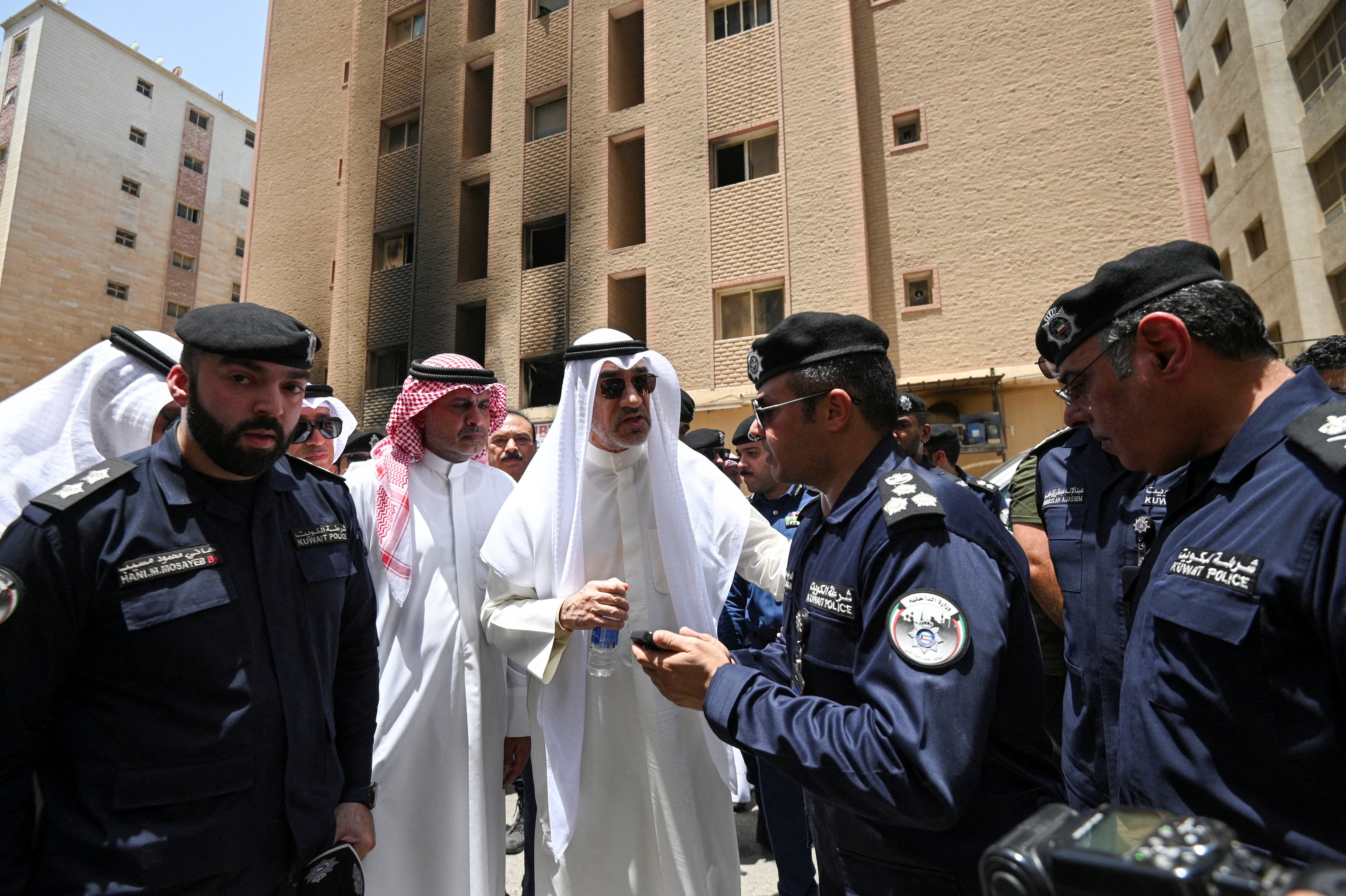 El viceprimer ministro y ministro de Defensa de Kuwait y ministro del Interior en funciones, Fahad Yusuf Al-Sabah, habla con agentes de policía frente al edificio quemado (REUTERS)