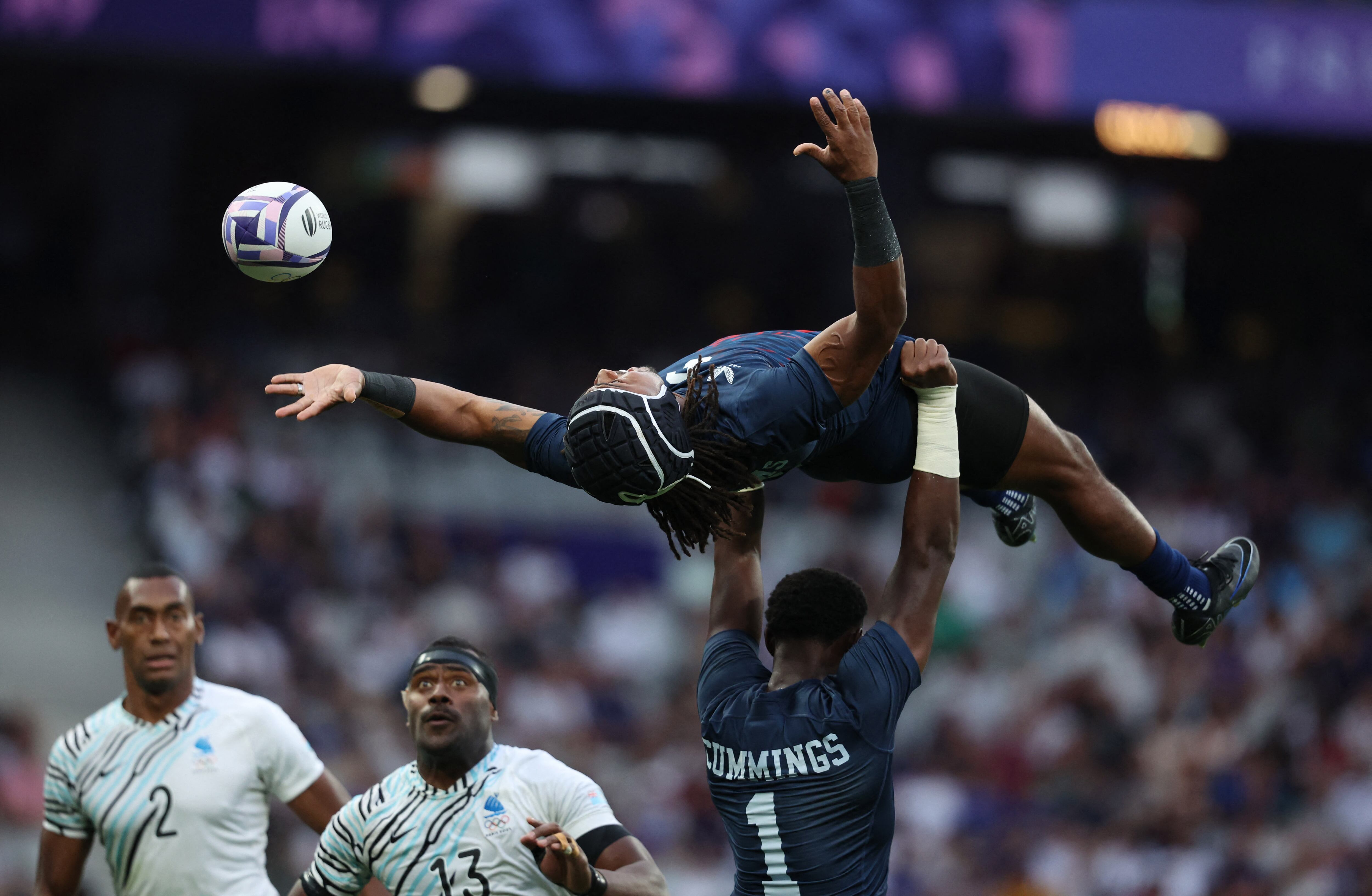 El jugador Kevon Williams, del seleccionado de rugby 7 de Estados Unidos, es levantado por su compañero Aaron Cummings durante el partido ante Fiji, en Saint-Dennis (REUTERS/Phil Noble)