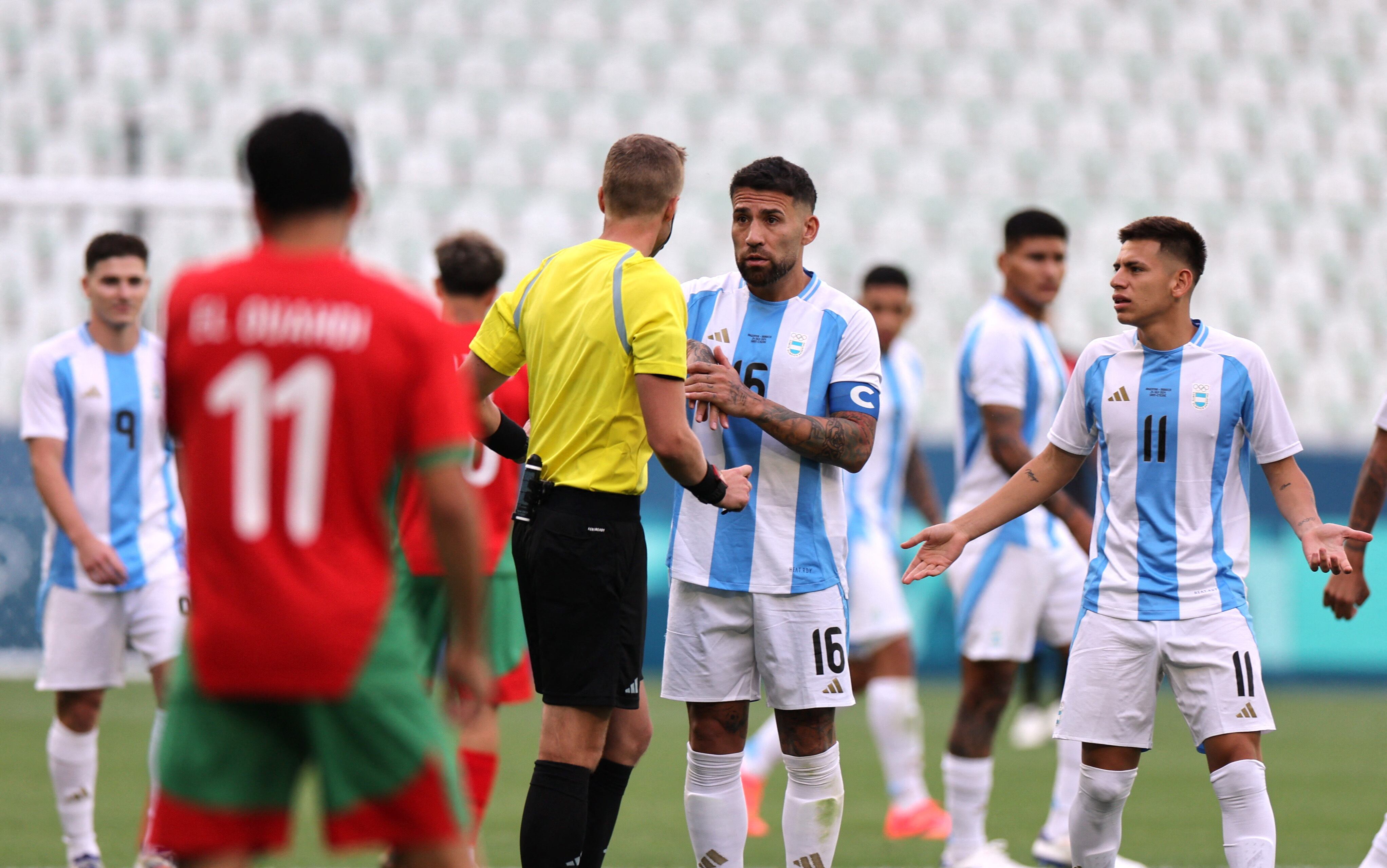 Nicolás Otamendi le pide explicaciones al árbitro sueco Glenn Nyberg, de bochornosa tarea. El Diablito Echeverri no comprende qué sucede (REUTERS/Thaier Al-Sudani)