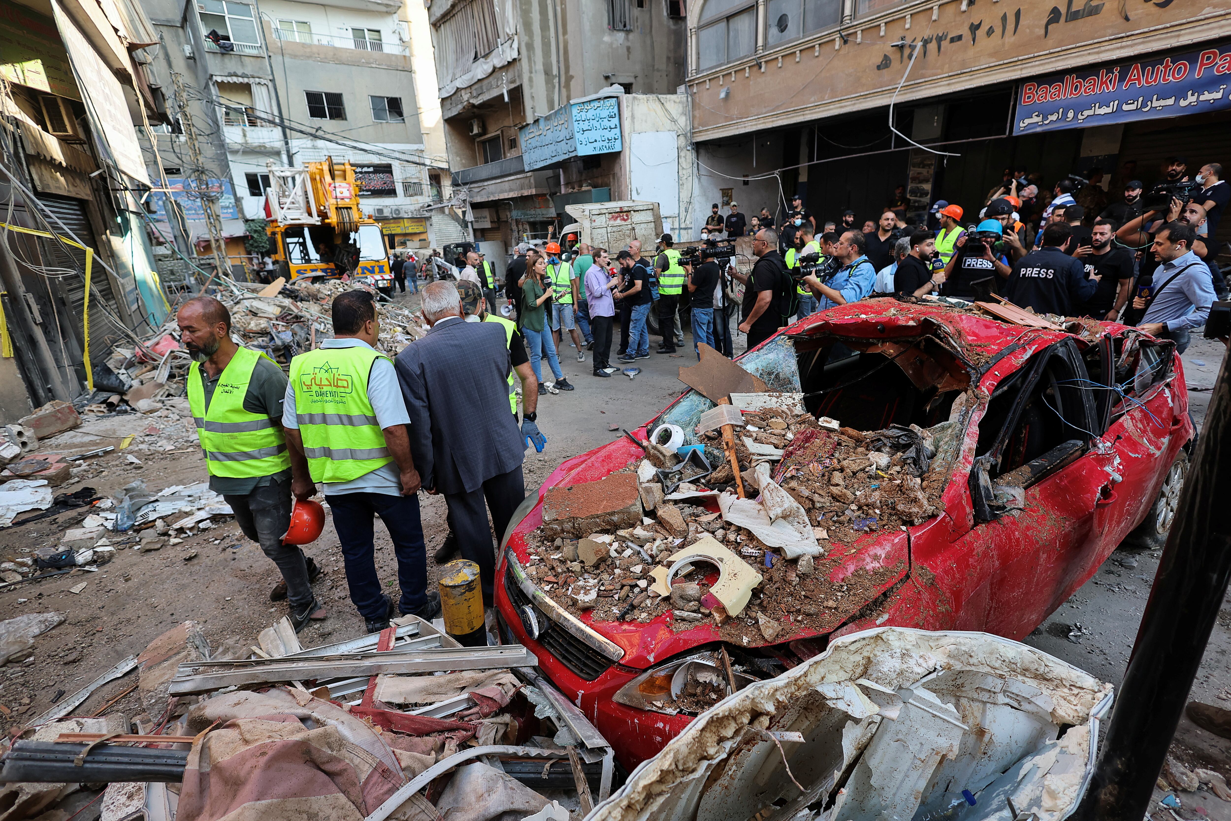 Un grupo de personas junto a un coche destruido, en el lugar de un ataque israelí en los suburbios del sur de Beirut (REUTERS/Amr Abdallah Dalsh)