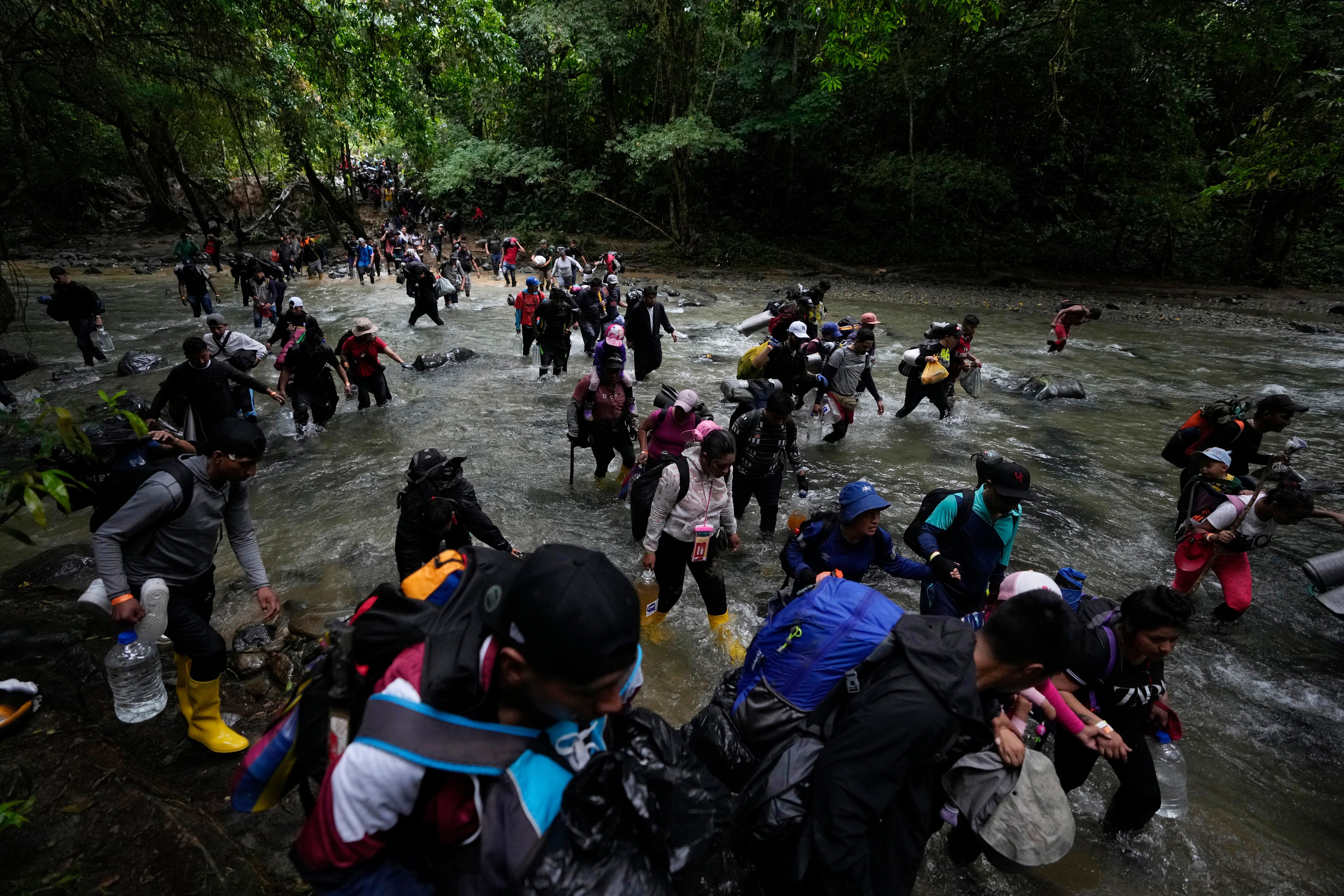 Migrantes, en su mayoría venezolanos, cruzan un río durante su viaje a través del Tapón del Darién desde Colombia a Panamá, con la esperanza de llegar a Estados Unidos, (AP Foto/Fernando Vergara, Archivo)