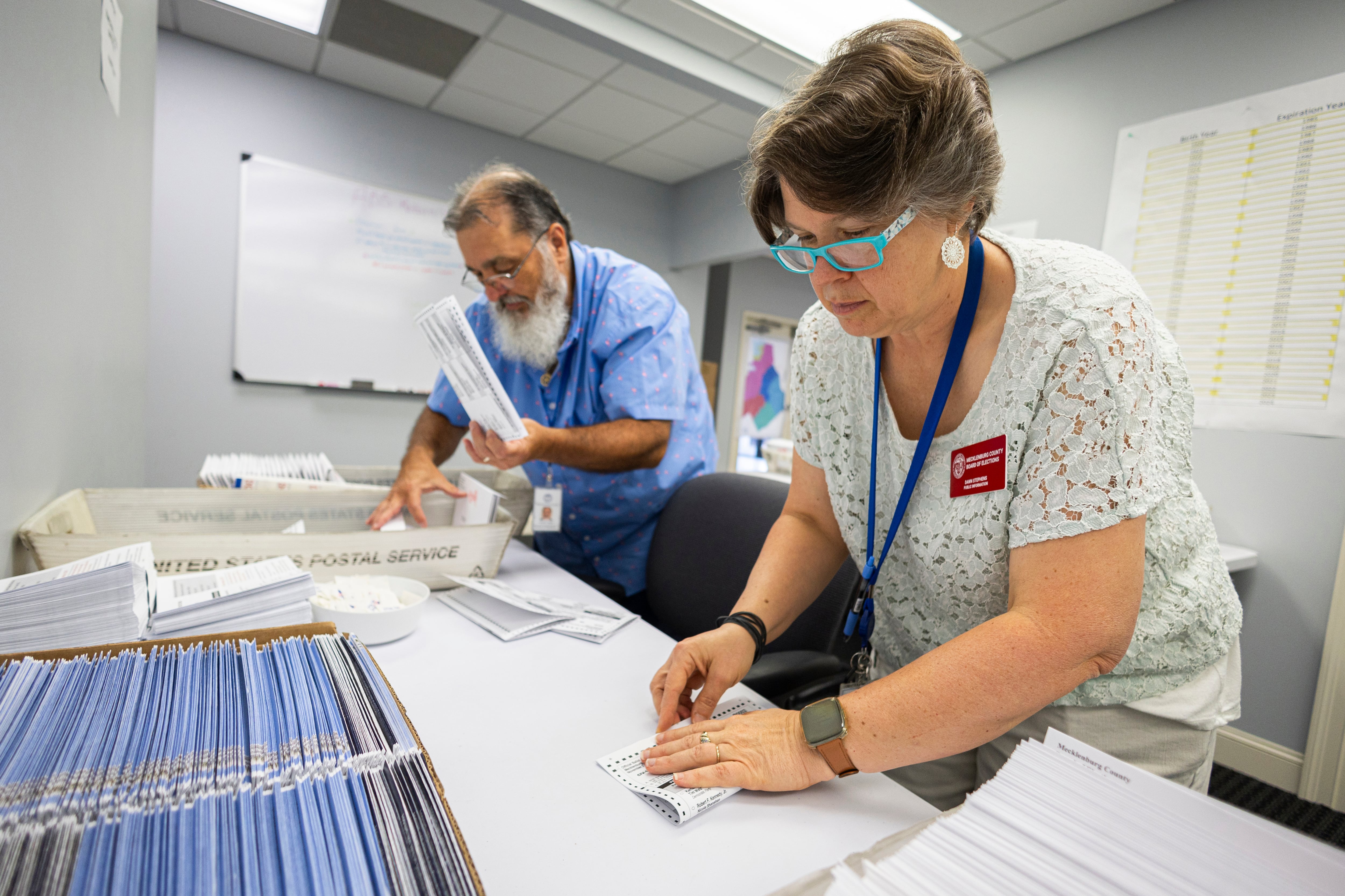 Dawn Stephens y Duane Taylor preparan boletas para votar que serán enviadas por correo postal, en la Junta Electoral del condado Mecklenburg, en Charlotte, Carolina del Norte. (AP Foto/Nell Redmond)