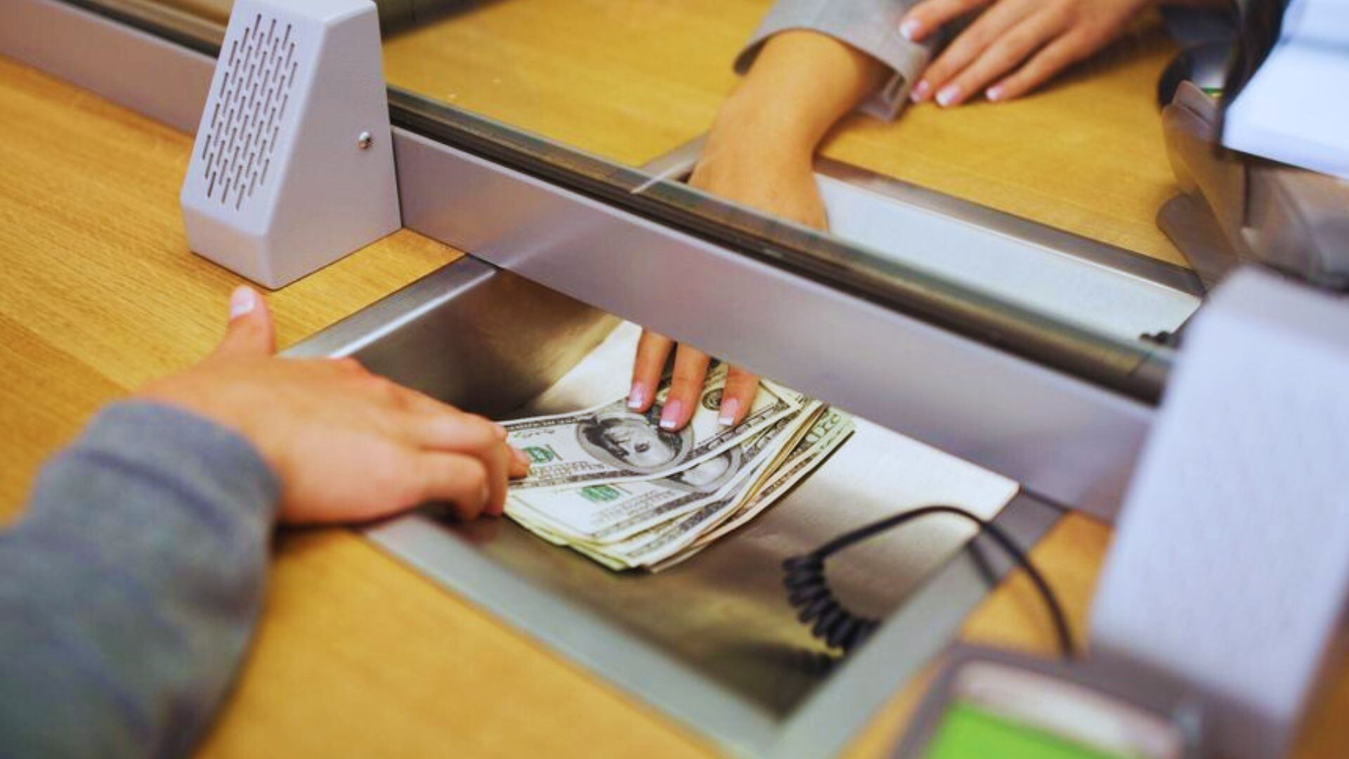 Mano depositando dólares en banco