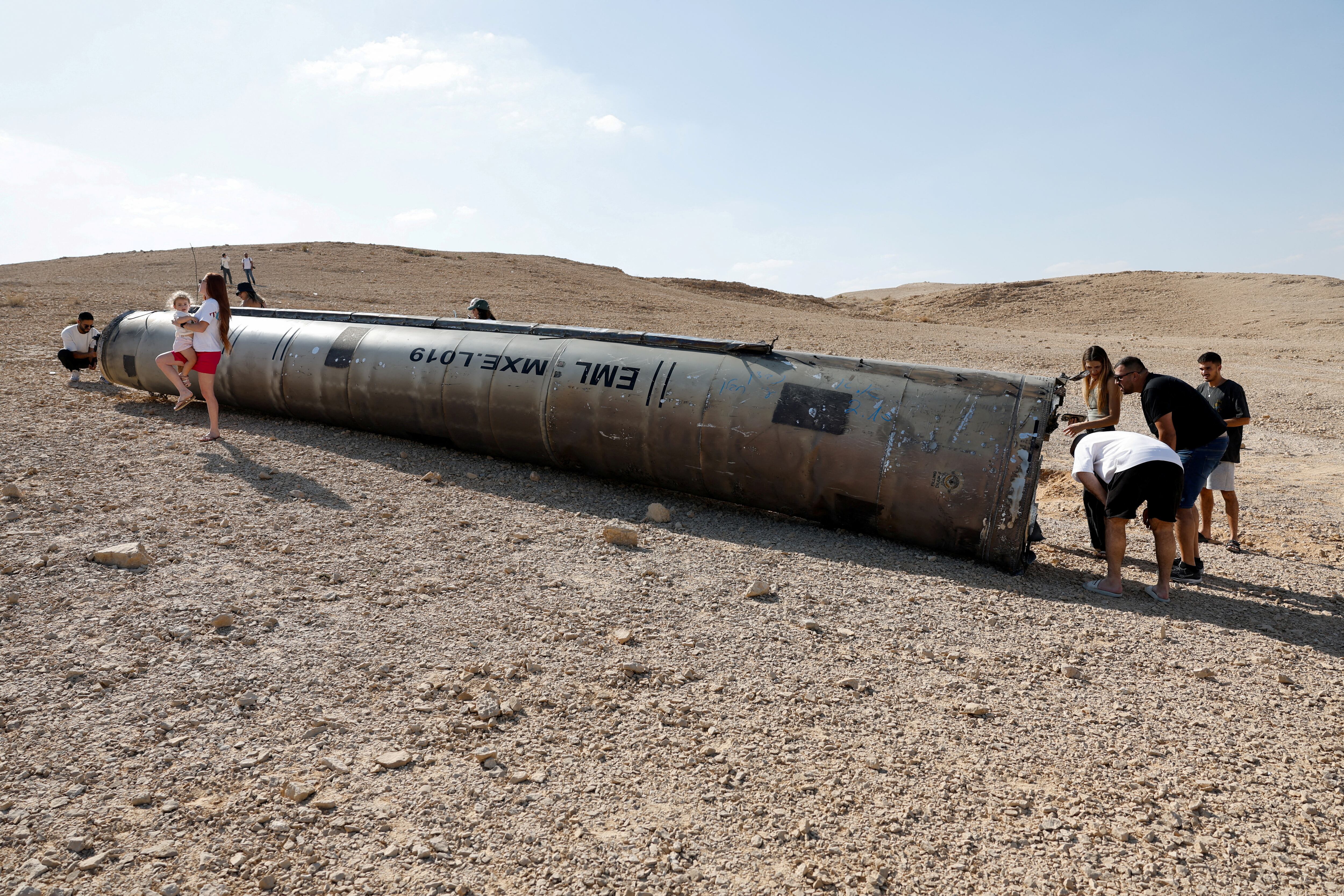 La gente observa los aparentes restos de un misil balístico que yacen en el desierto, tras un ataque de Irán contra Israel, cerca de la ciudad sureña de Arad, Israel, el 2 de octubre de 2024