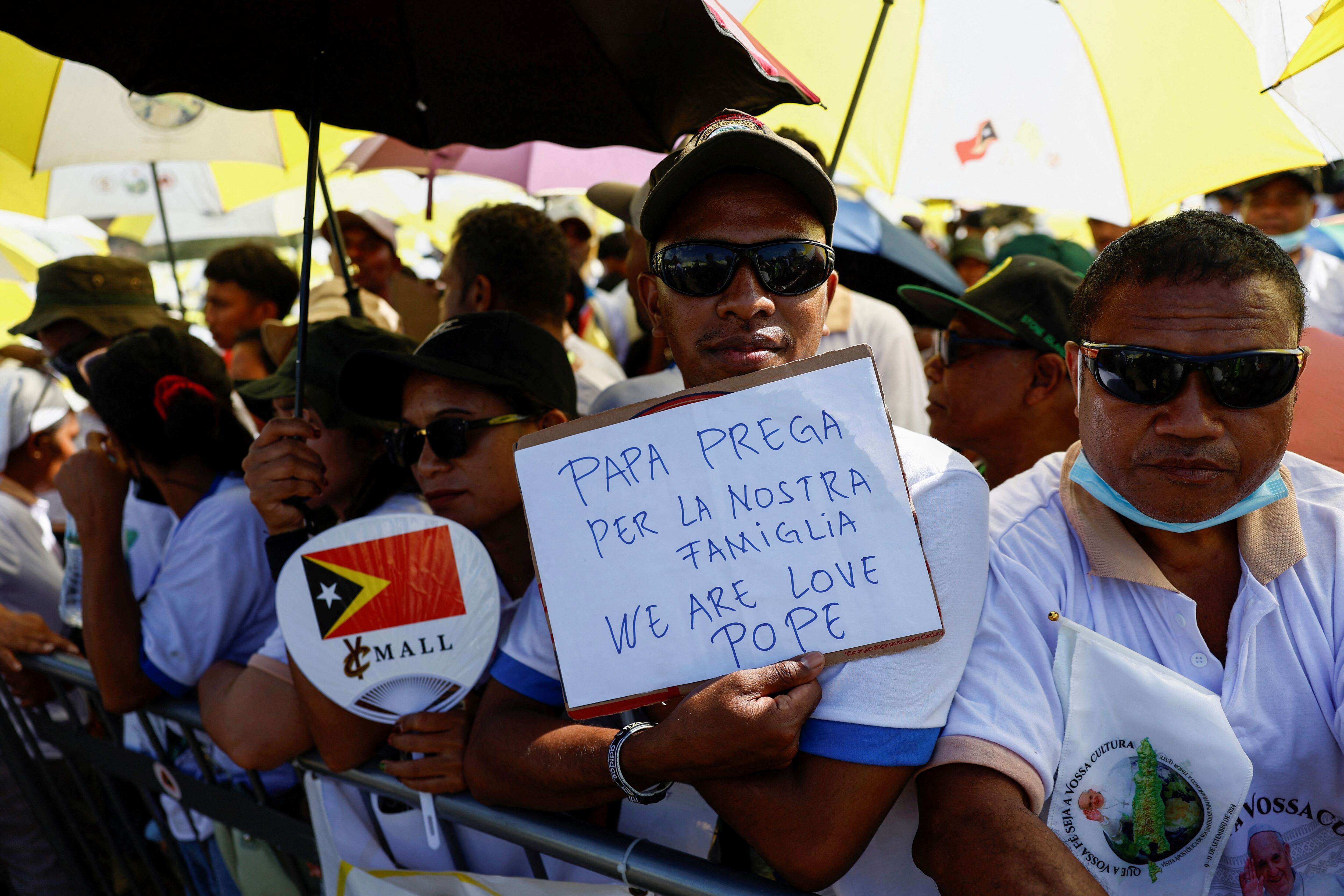 Un hombre con un cartel que lee "Papa reza por nuestra familia nosotros somos amor Papa".