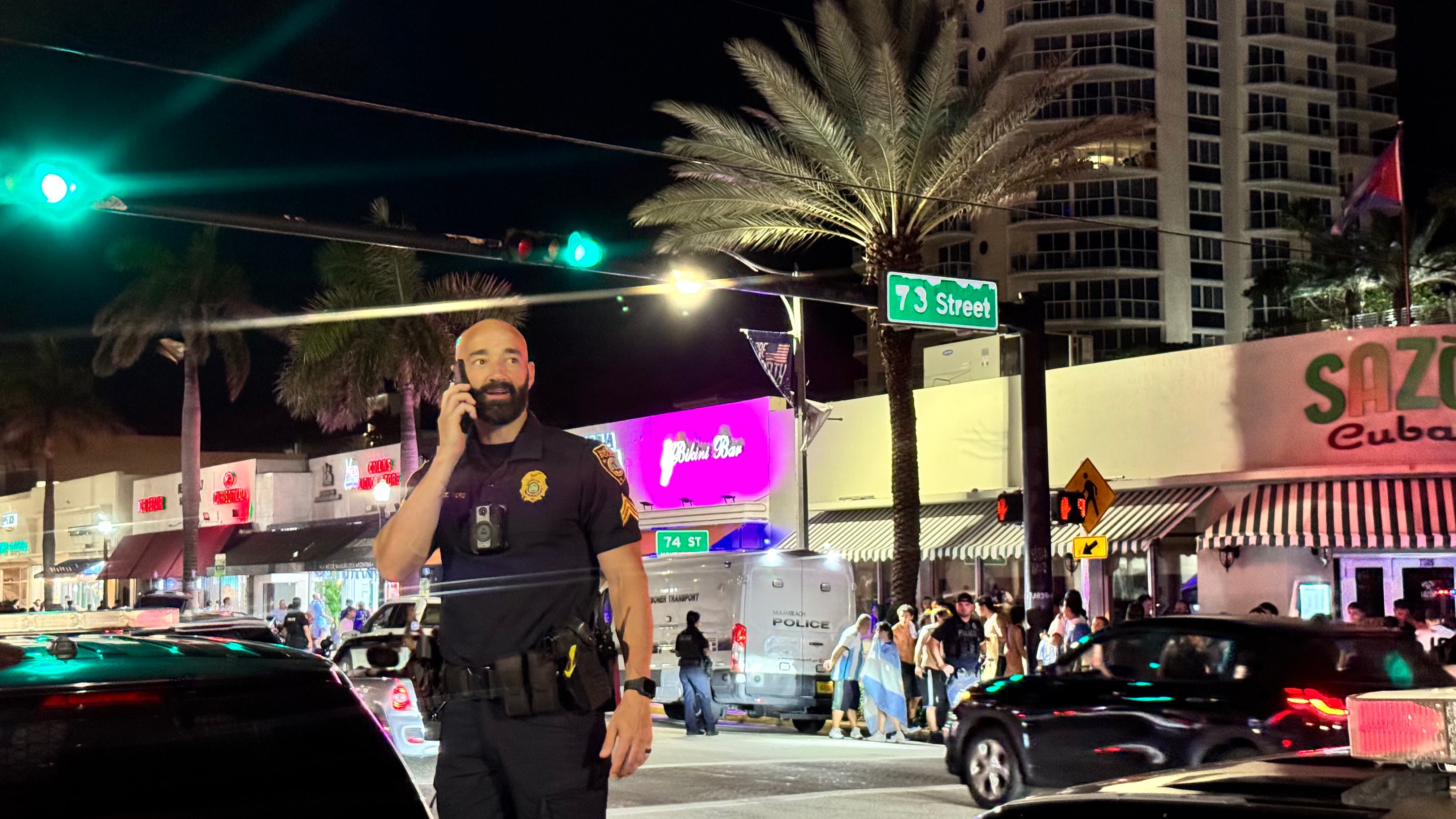 Una multitud de hinchas argentinos, vestidos con camisetas de la selección y agitando banderas celestes y blancas, celebra en las calles de Miami Beach durante la noche. La gente se muestra eufórica, tomando fotos y cantando, en una atmósfera festiva y llena de emoción tras la victoria de la Selección Argentina en la Copa América.