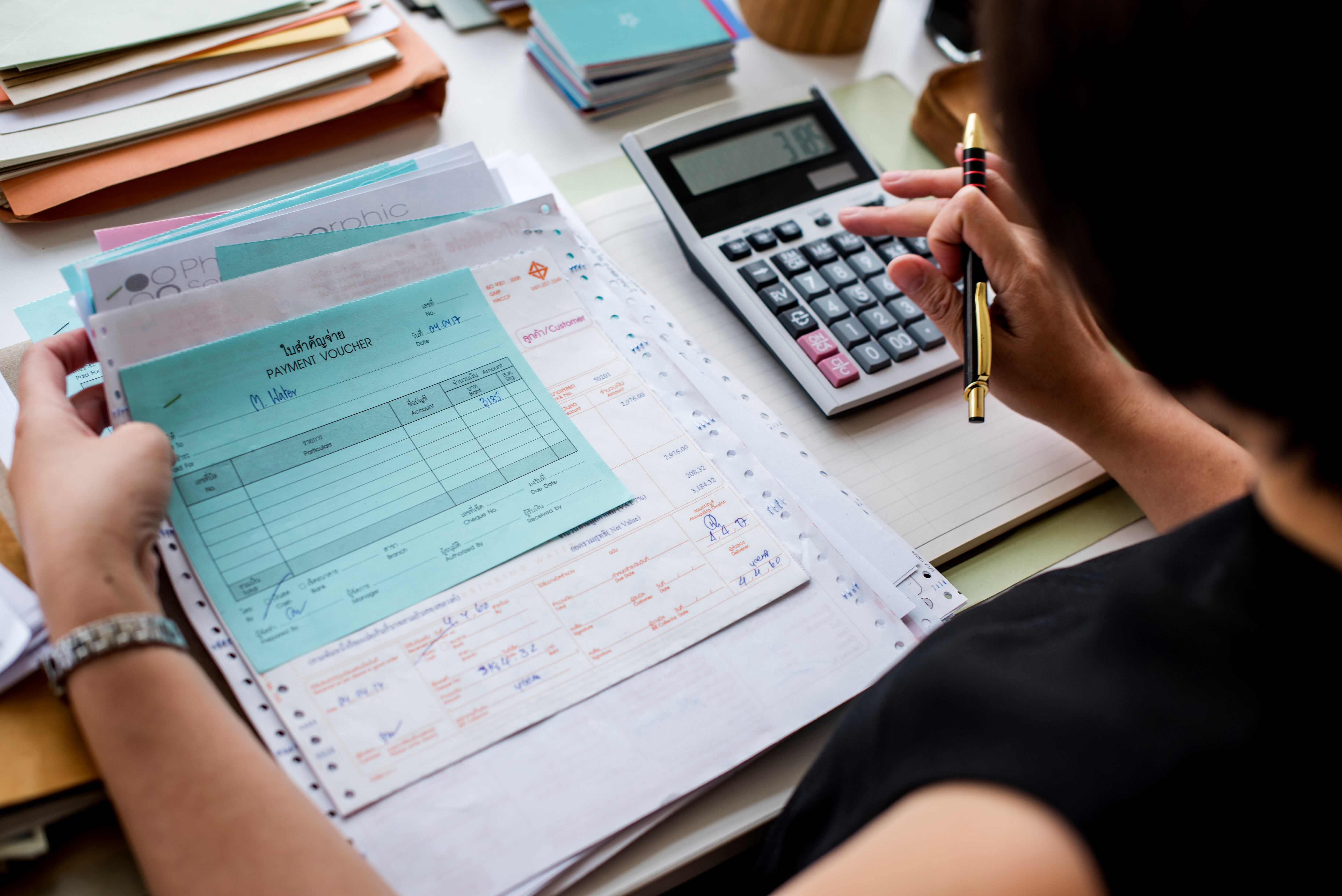 Mujer haciendo facturas con la ayuda de una calculadora (Freepik)