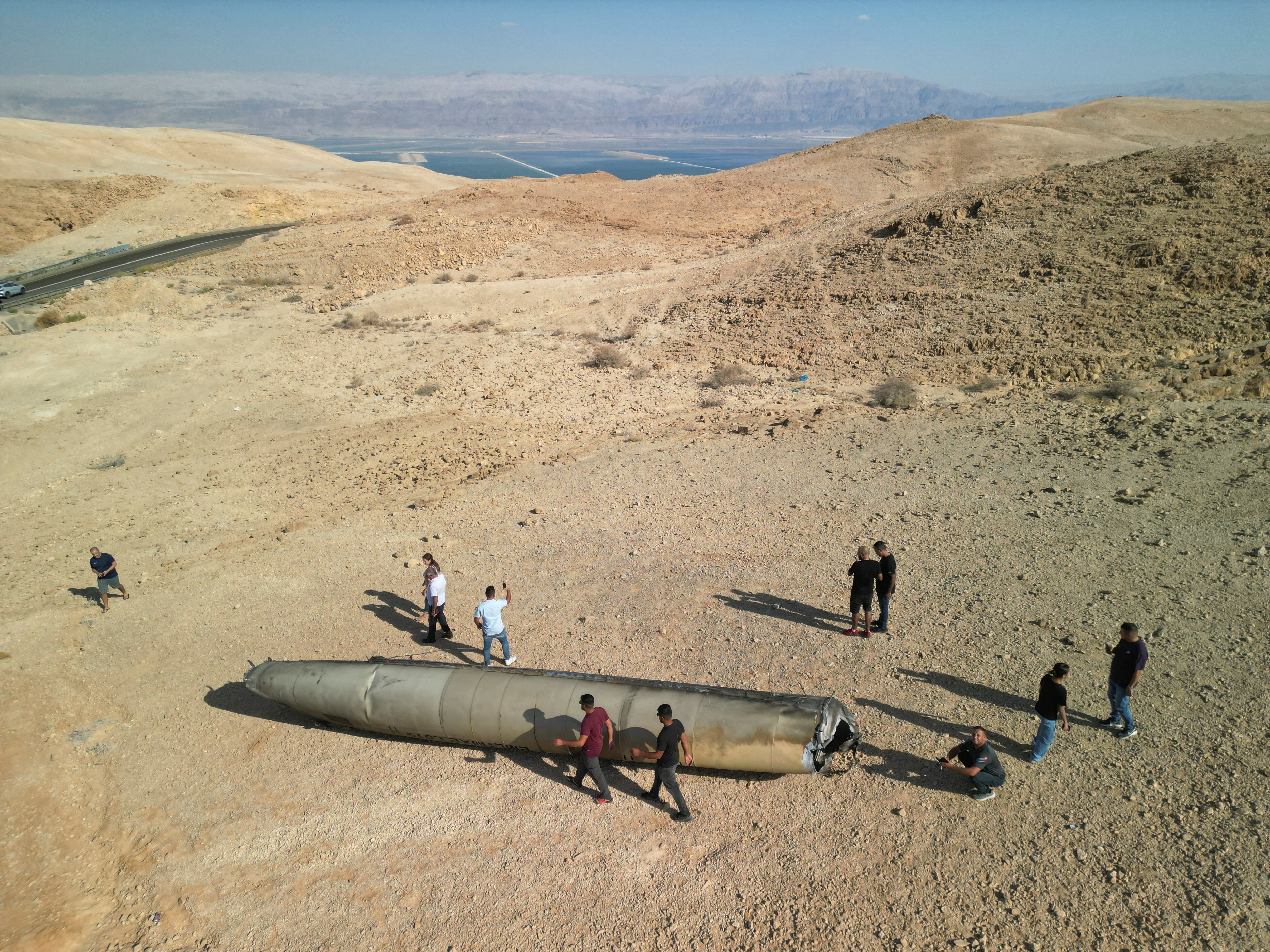 Una vista de un dron muestra a personas paradas alrededor de los aparentes restos de un misil balístico que yacen en el desierto