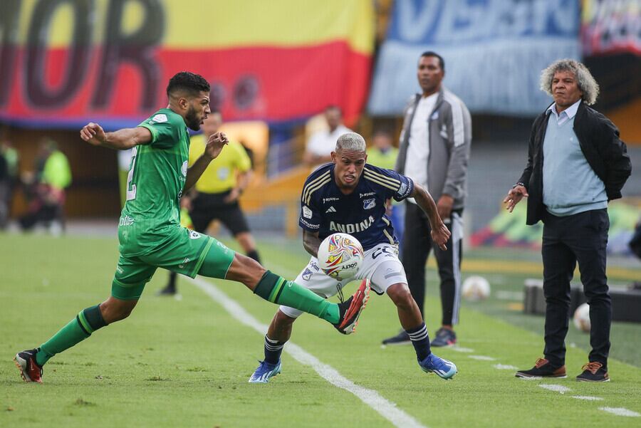 Daniel Polanco y Deivin Alfonzo, ambos defensores en la disputa de una pelota, al fondo, el técnico de Millonarios, Alberto Gamero-crédito John Paz/Colprensa