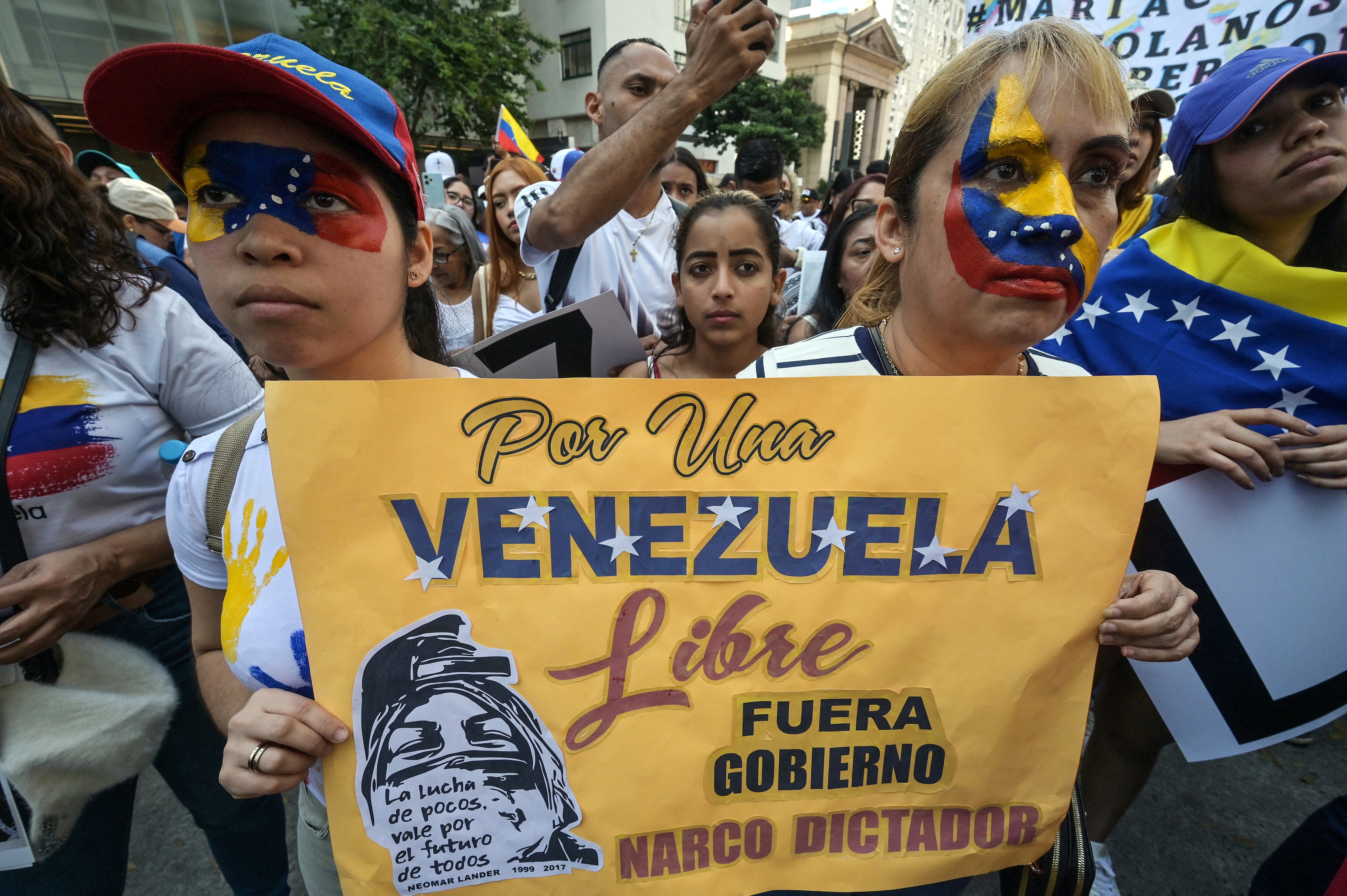 Dos ciudadanos venezolanos, con sus caras pintadas con la bandera de Venezuela, sostienen una pancarta contra el presidente venezolano Nicolás Maduro durante una protesta en apoyo a la oposición venezolana en la Avenida Paulista en Sao Paulo, Brasil, el 28 de julio de 2024 (Foto de Nelson ALMEIDA / AFP)