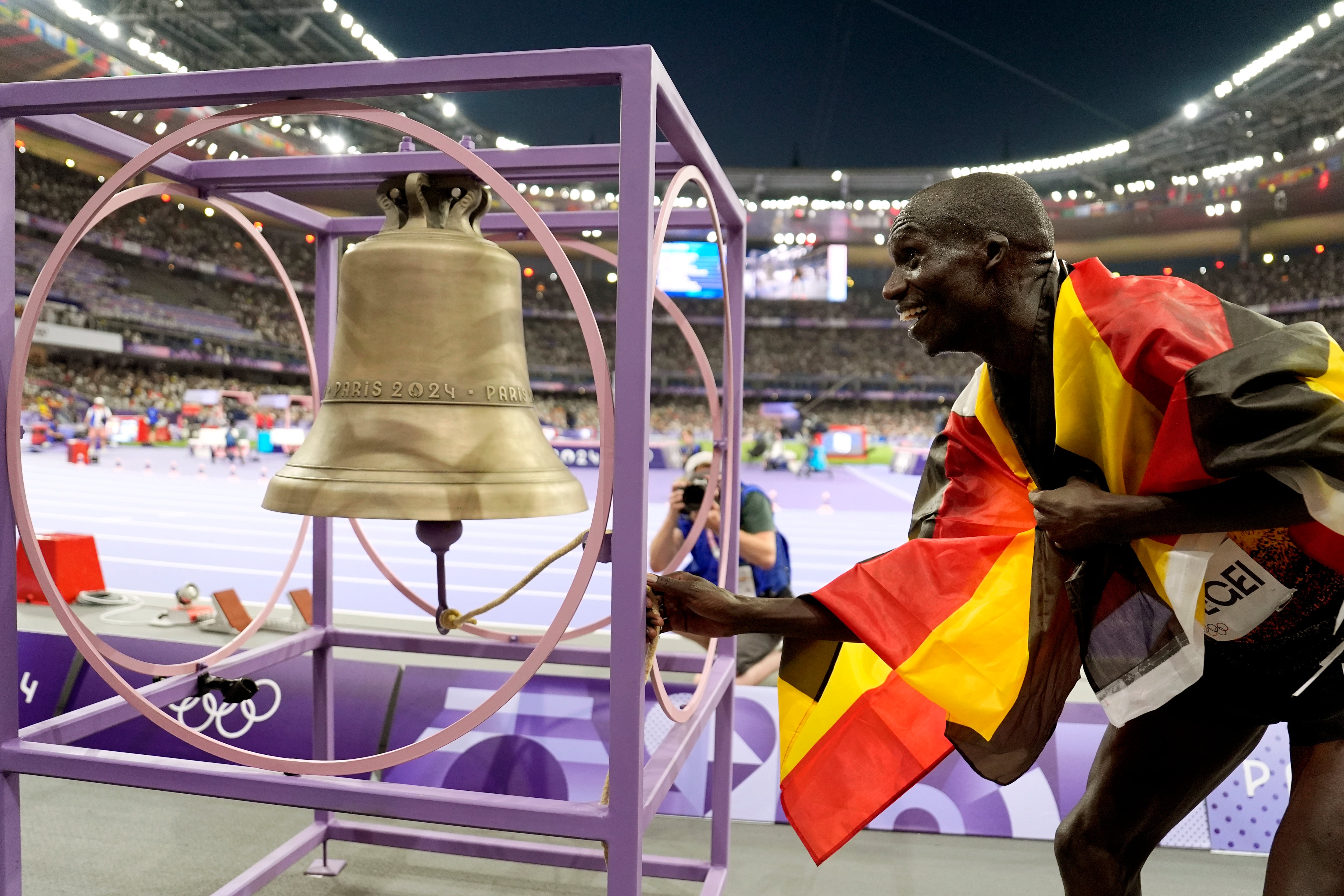 El ugandés Joshua Cheptegei suena la campana tras ganar los 10.000 metros de los Juegos Olímpicos de París (AP Foto/Matthias Schrader)