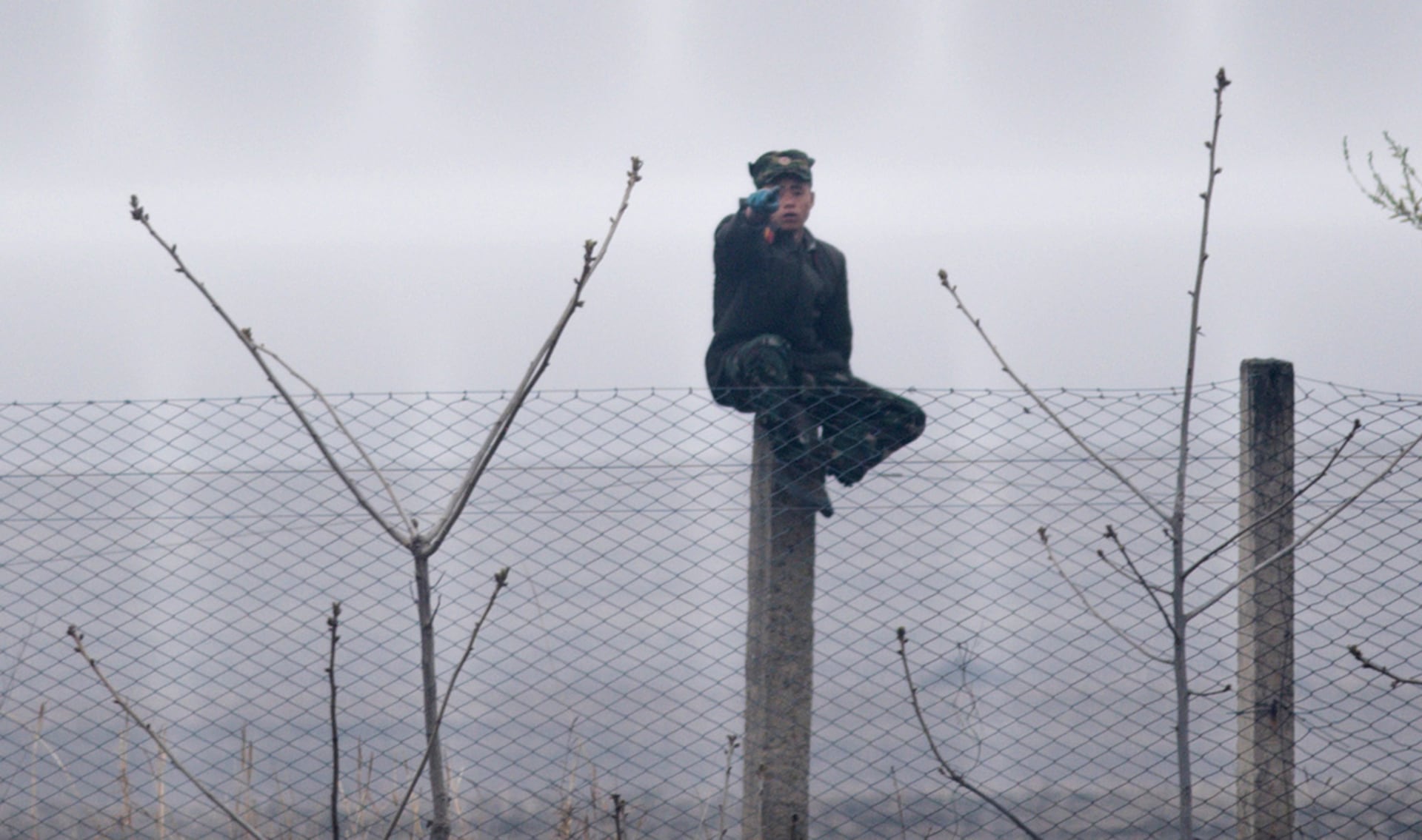 Un soldado norcoreano se sienta en una valla cerca de Sinuiju, frente a la ciudad fronteriza china de Dandong  (AFP PHOTO / Johannes EISELE)