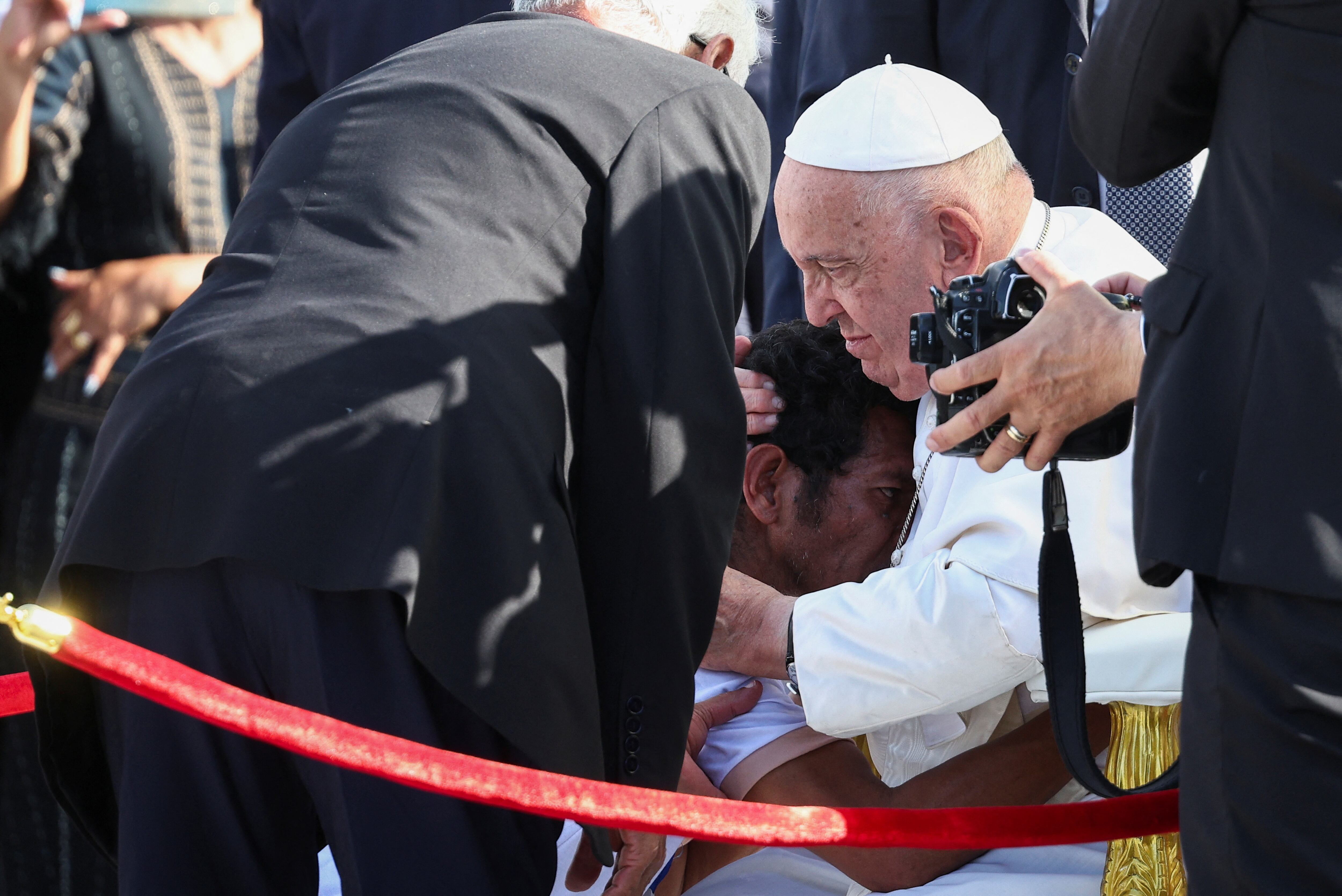 El Papa Francisco abraza a una persona mientras asisten a la Santa Misa en la Explanada de Taci Tolu durante su viaje apostólico a Asia.