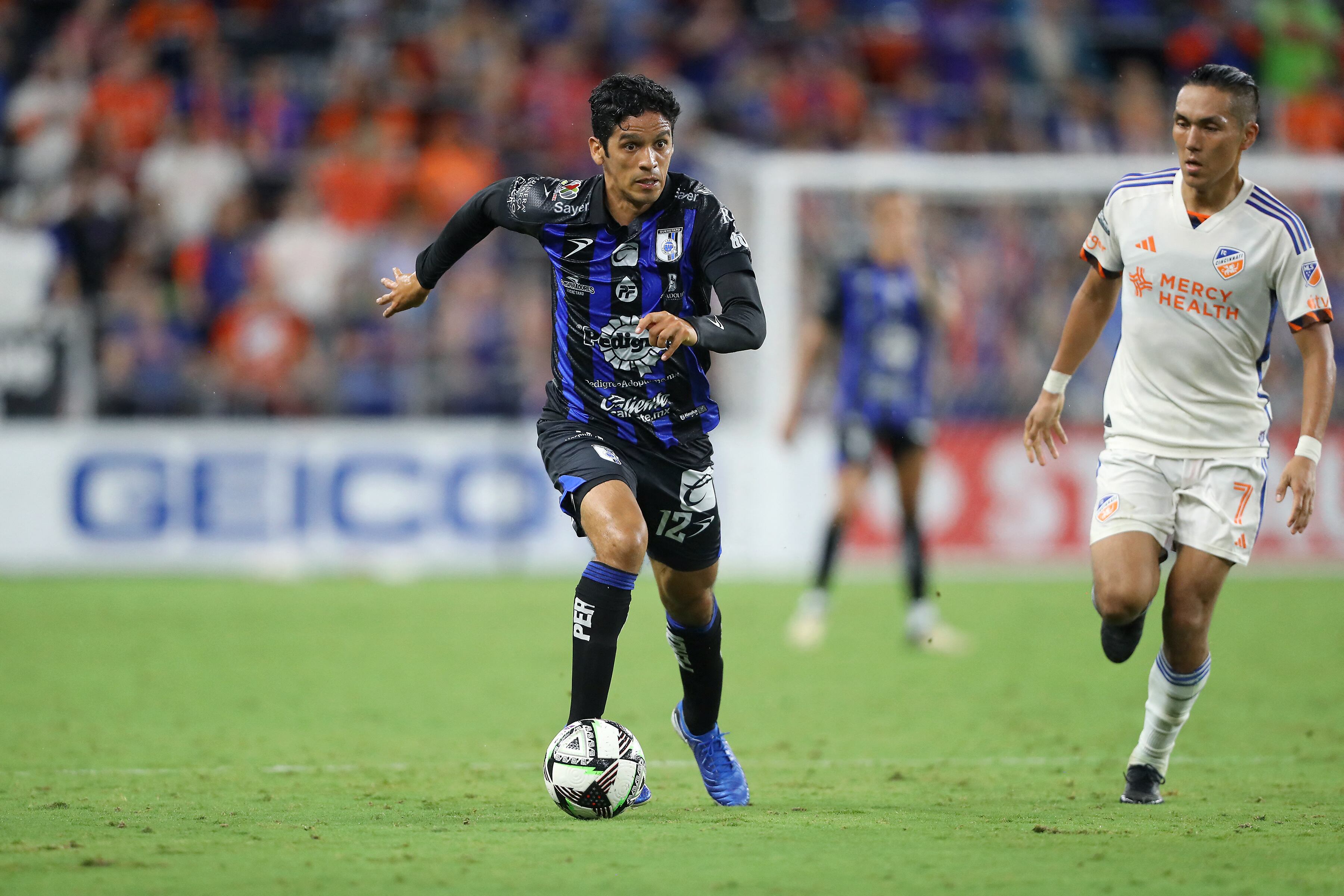 Aug 1, 2024; Cincinnati, Ohio, USA; Queretaro midfielder Jaime Gomez (12) controls the ball as FC Cincinnati forward Yuya Kubo (7) defends during the second half at TQL Stadium. Mandatory Credit: Joseph Maiorana-USA TODAY Sports