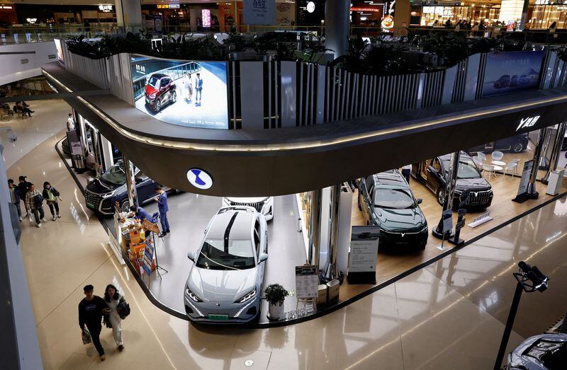 Modelos de vehículos eléctricos (VE) se exhiben en los stands de Denza, una empresa conjunta entre Mercedes-Benz Group AG y BYD Auto, y el fabricante chino de VE Voyah, en un centro comercial de Pekín, China, el 3 de noviembre de 2023 (REUTERS/Tingshu Wang/Archivo)