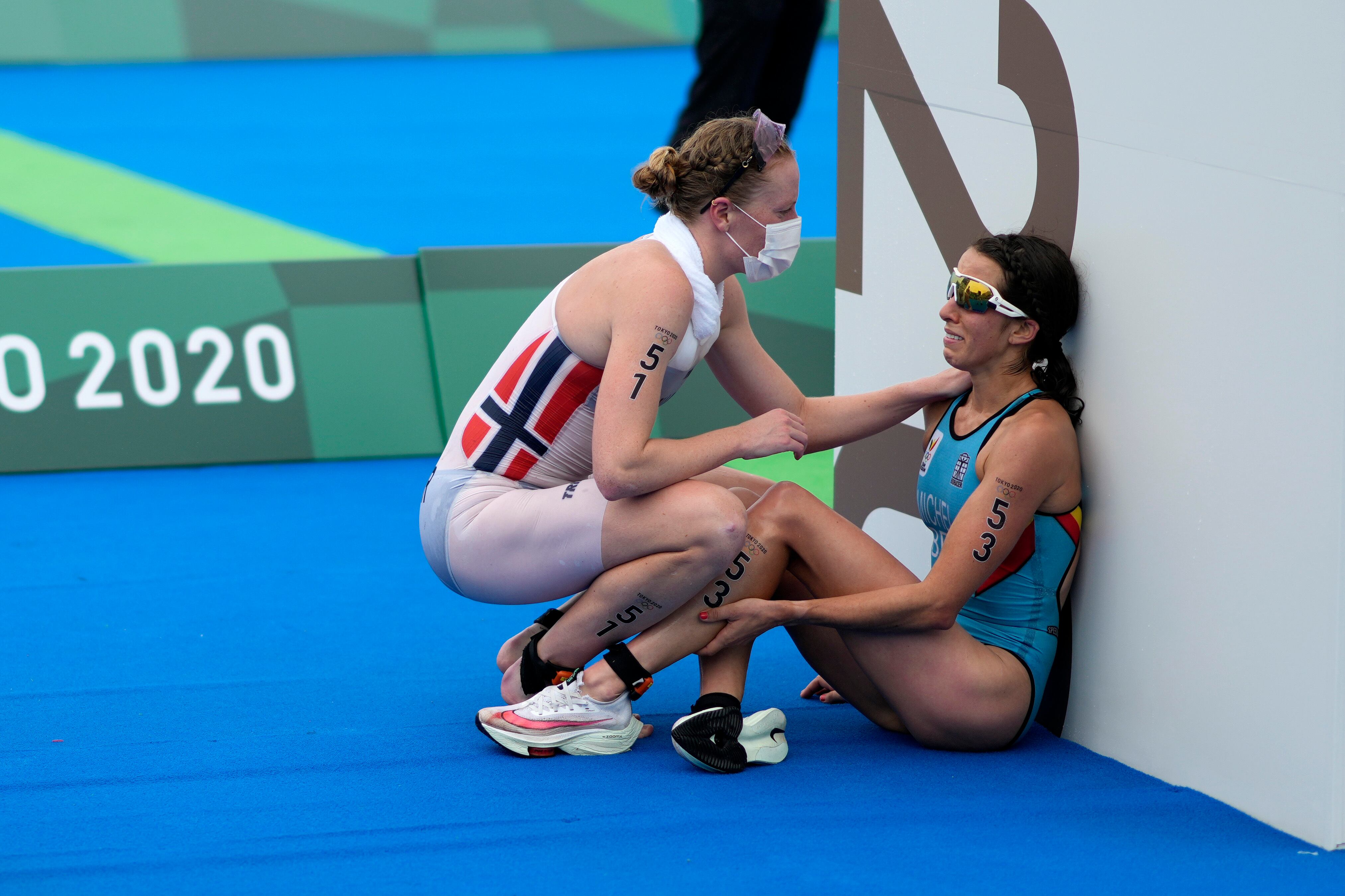 La atleta Claire Michel recibe ayuda su rival tras completar la prueba en el río Sena