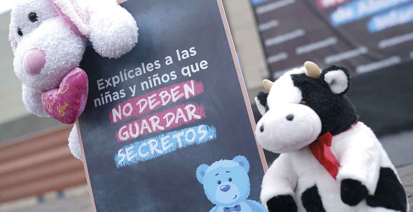 Un cartel contra el abuso sexual infantil rodeado de peluches infantiles (aldeas Infantiles SOS Perú)