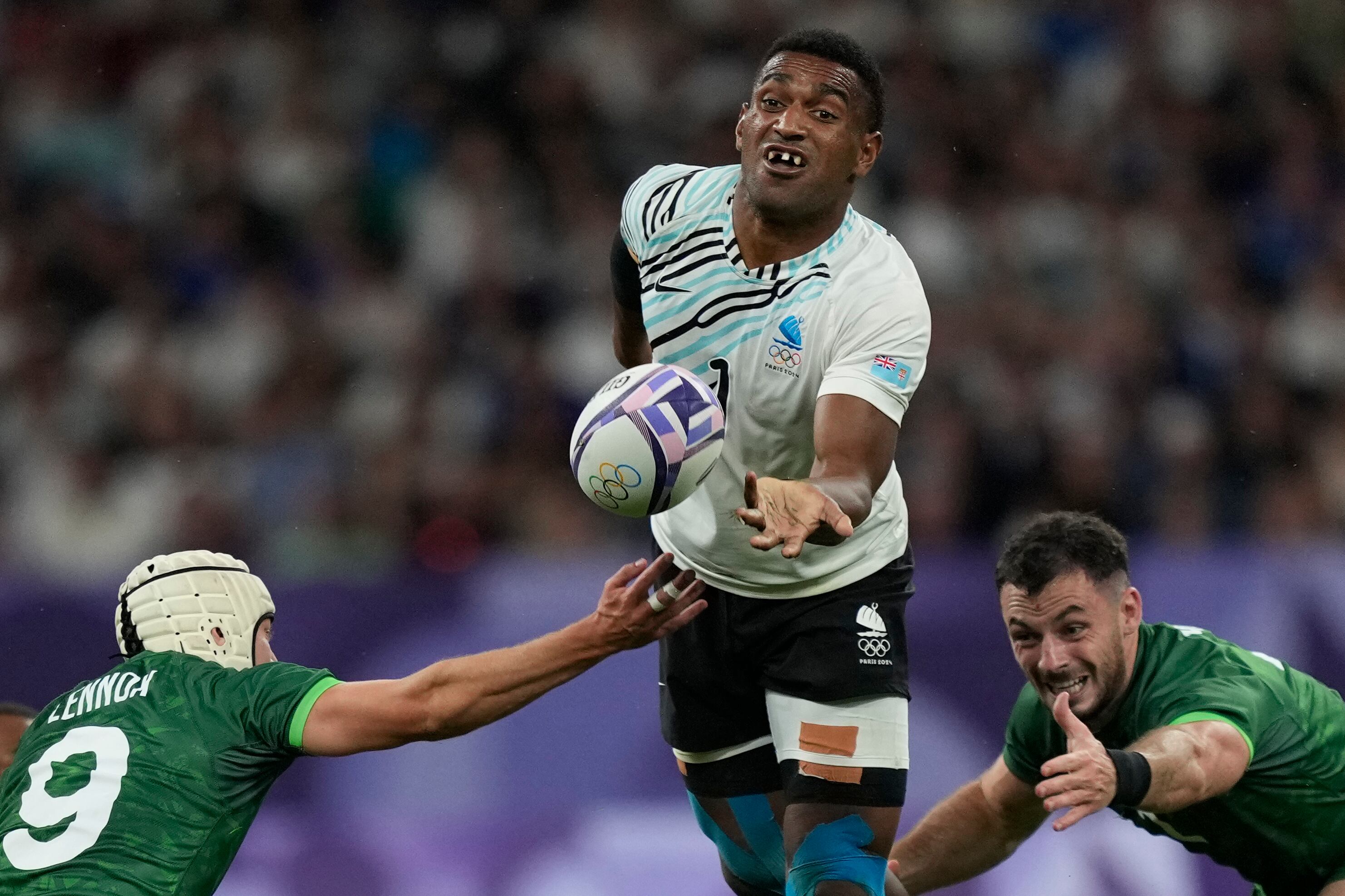 El fiyiano Joji Nasova pasa el balón ante el irlandés Hugo Lenox en los cuartos de final del torneo de rugby sevens de los Juegos Olímpicos de París, el jueves 25 de julio de 2024, en Saint-Denis, Francia. (AP Foto/Tsvangirayi Mukwazhi)