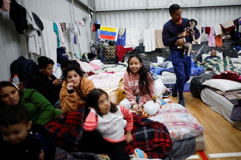 El refugiado venezolano Xavier Velasquez sostiene a su perro en un refugio después de que su casa fuera destruida por las inundaciones, en Porto Alegre, estado de Rio Grande do Sul (REUTERS/Adriano Machado)