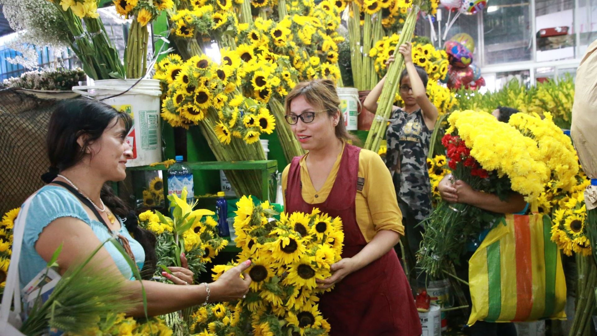 Vendedoras de flores amarillas intercambian claveles en el marcado del Rímac.