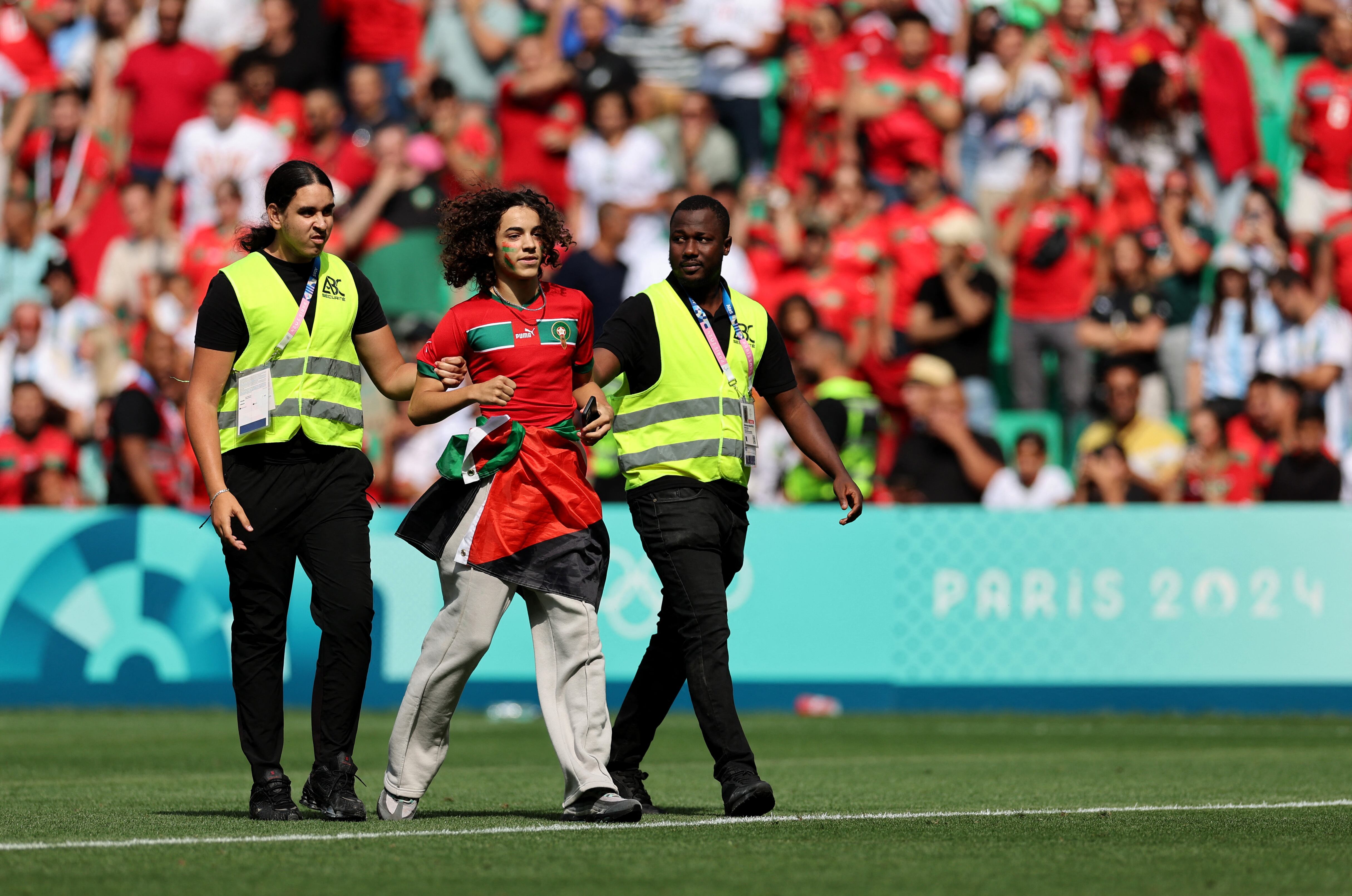 Uno de los invasores del campo de juego en Saint-Ettiene es detenido por el personal de seguridad en los Juegos Olímpicos (REUTERS/Thaier Al-Sudani)