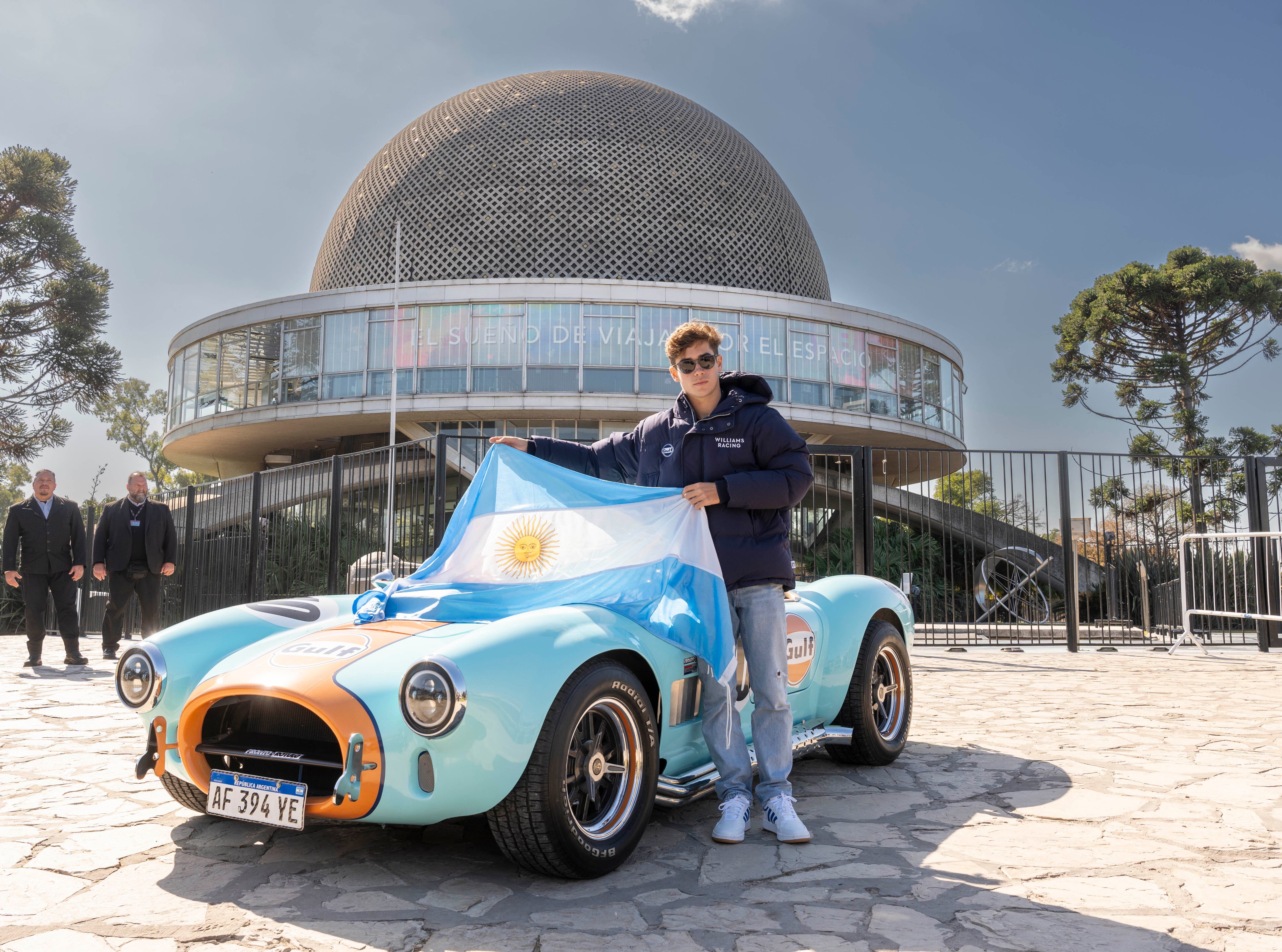 Franco Colapinto con la bandera argentina y el Shelby Cobra en el Planetario (Gulf Tour Buenos Aires - Franco Colapinto. Crédito: Juan Lopetegui)