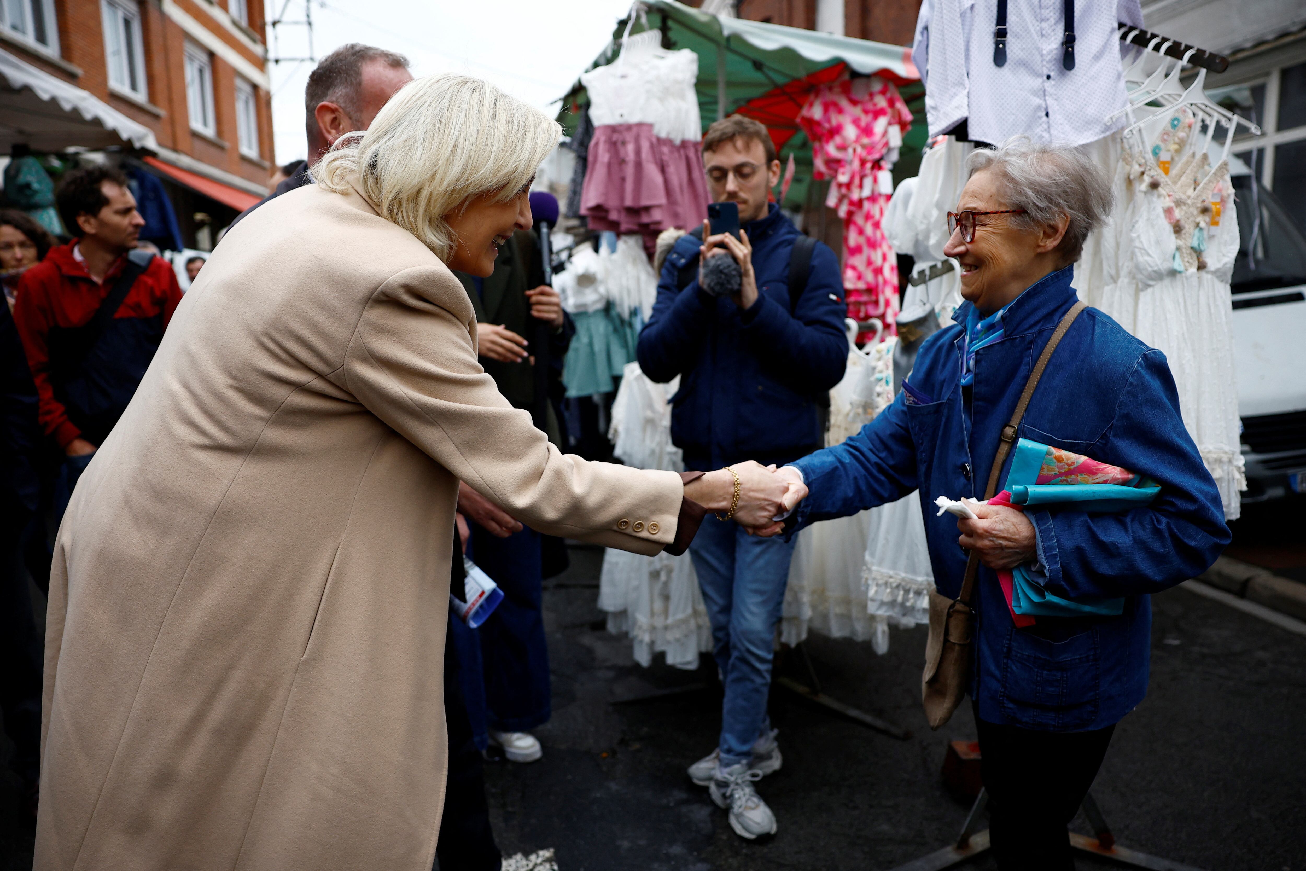 Marine Le Pen, líder de extrema derecha francesa y candidata del partido de extrema derecha Agrupación Nacional (Rassemblement National - RN) en las próximas elecciones parlamentarias, le da la mano a una residente mientras hace campaña en un mercado en Henin-Beaumont, al norte de Francia, en junio. 14, 2024. REUTERS/Sarah Meyssonnier
