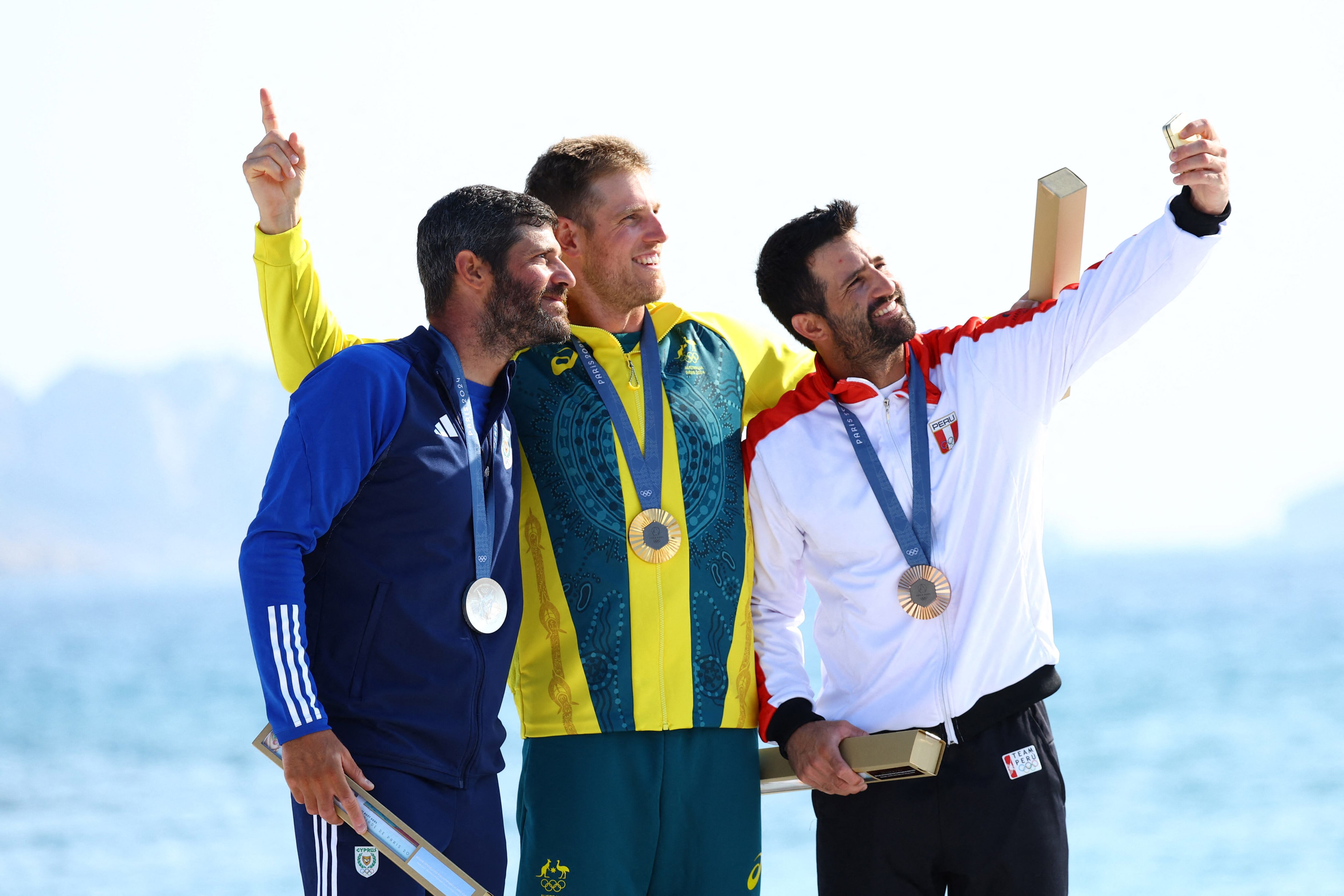 Paris 2024 Olympics - Sailing - Men's Dinghy Victory Ceremony - Marseille Marina, Marseille, France - August 07, 2024. Gold medallist Matt Wearn of Australia poses on the podium with silver medallist Pavlos Kontides of Cyprus and bronze medallist Stefano Peschiera of Peru. REUTERS/Andrew Boyers