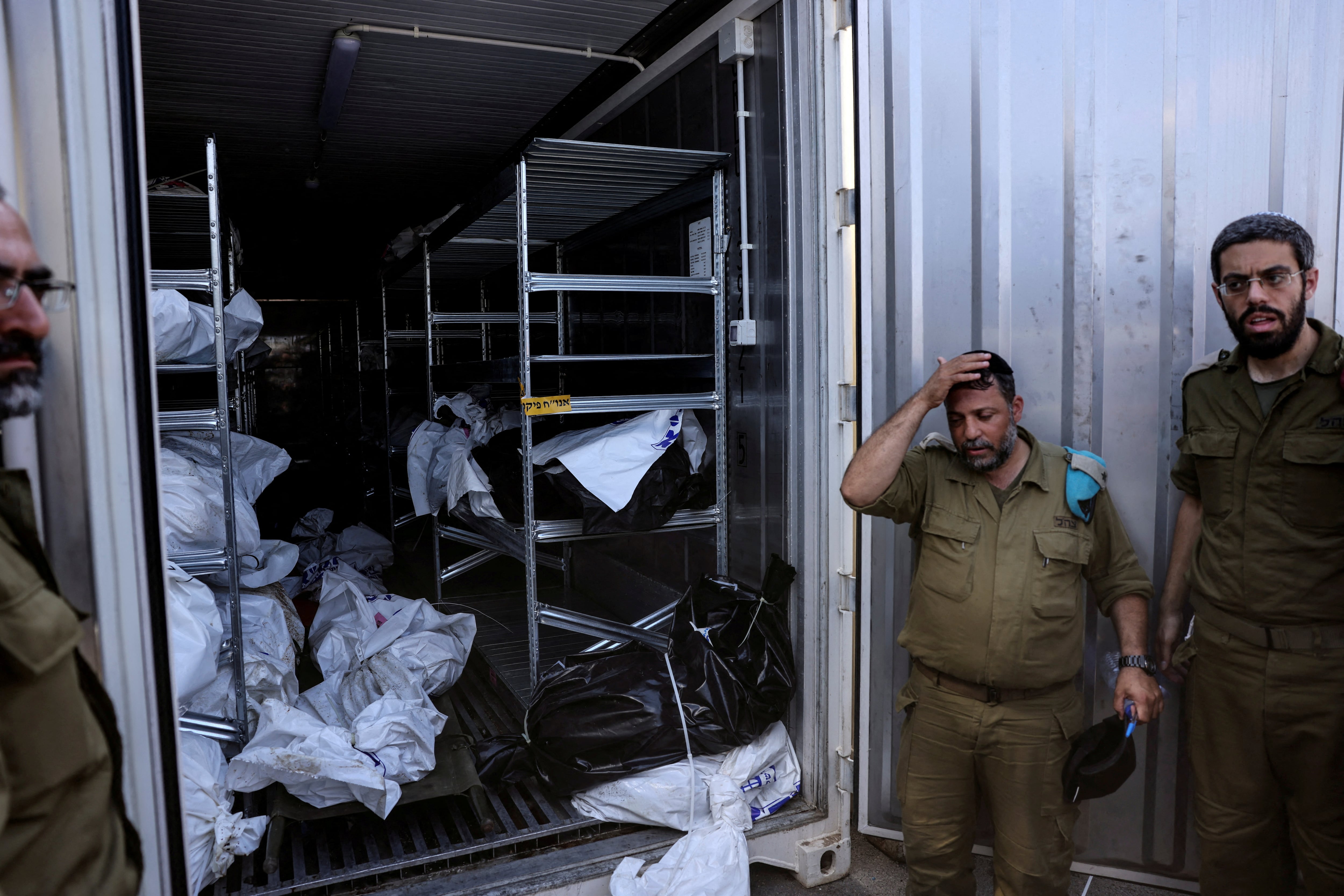 Oficiales militares israelíes junto a un contenedor en el que se almacenan los cuerpos de los muertos antes de que llamen a sus familiares para identificarlos