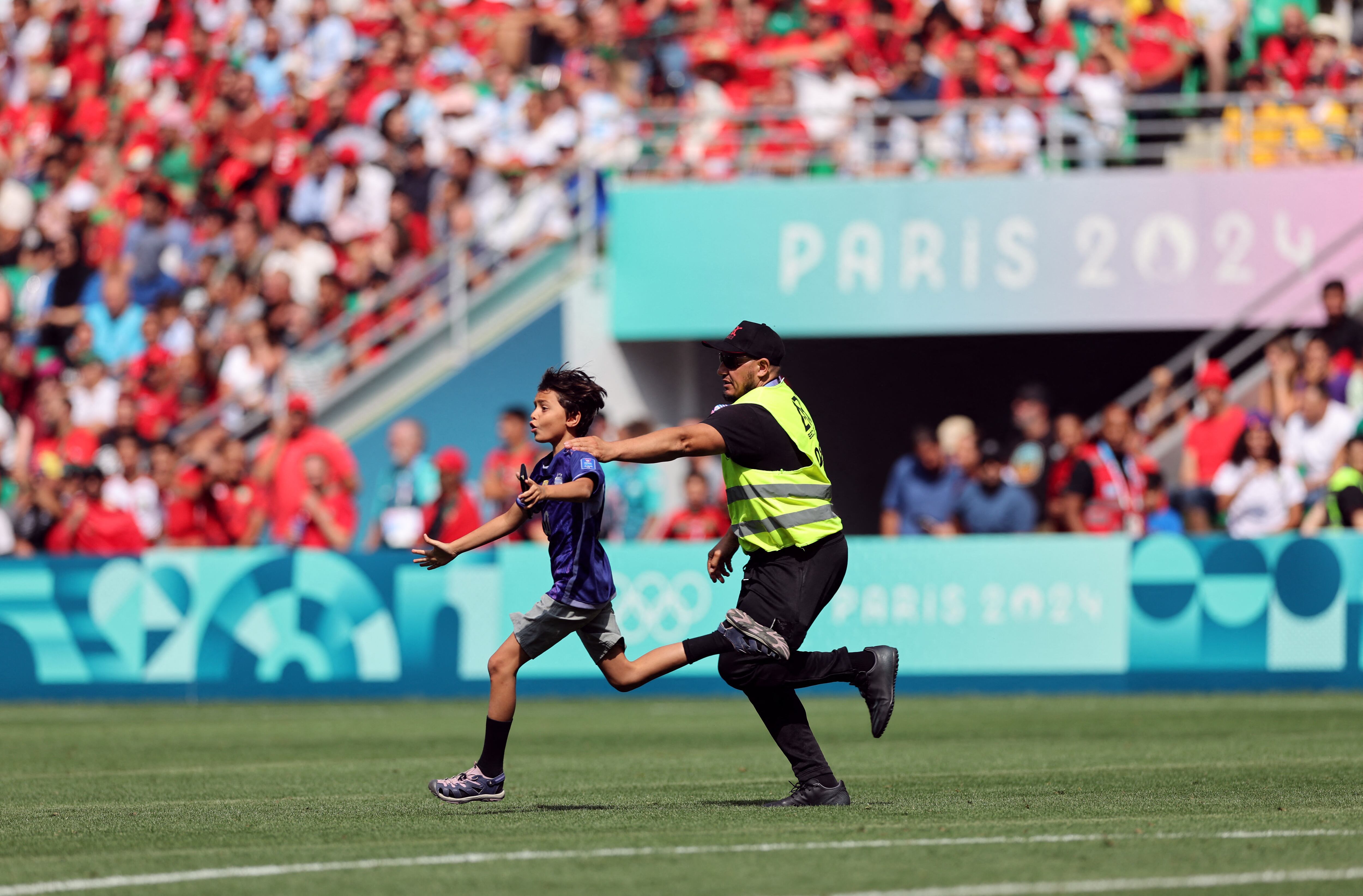 Un niño saltó al campo de juego y un oficial de seguridad privada corre para atraparlo. Caos en Argentina-Marruecos (REUTERS/Thaier Al-Sudani)