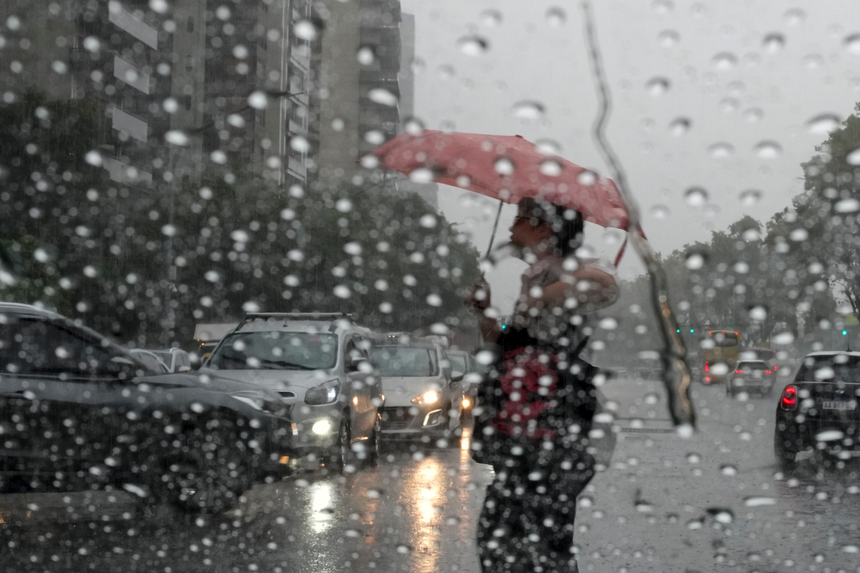 Un peatón sostiene un paraguas mientras cruza una calle durante un aguacero, en Buenos Aires, Argentina, el 20 de marzo de 2024. (AP Foto/Natacha Pisarenko)