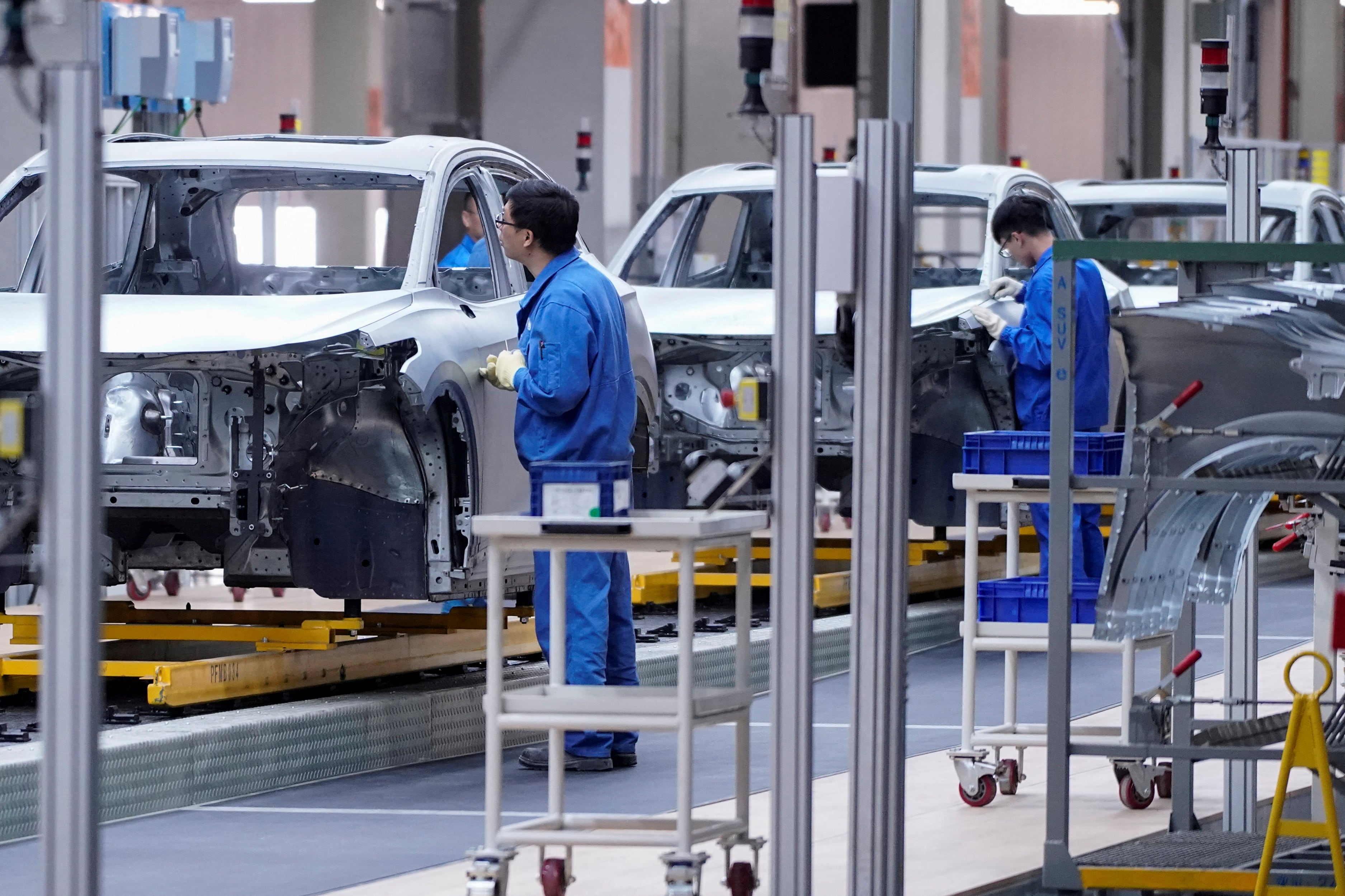 Empleados trabajan en la línea de montaje de una planta de vehículos eléctricos SAIC Volkswagen MEB en Shanghái, China (REUTERS/Aly Song)