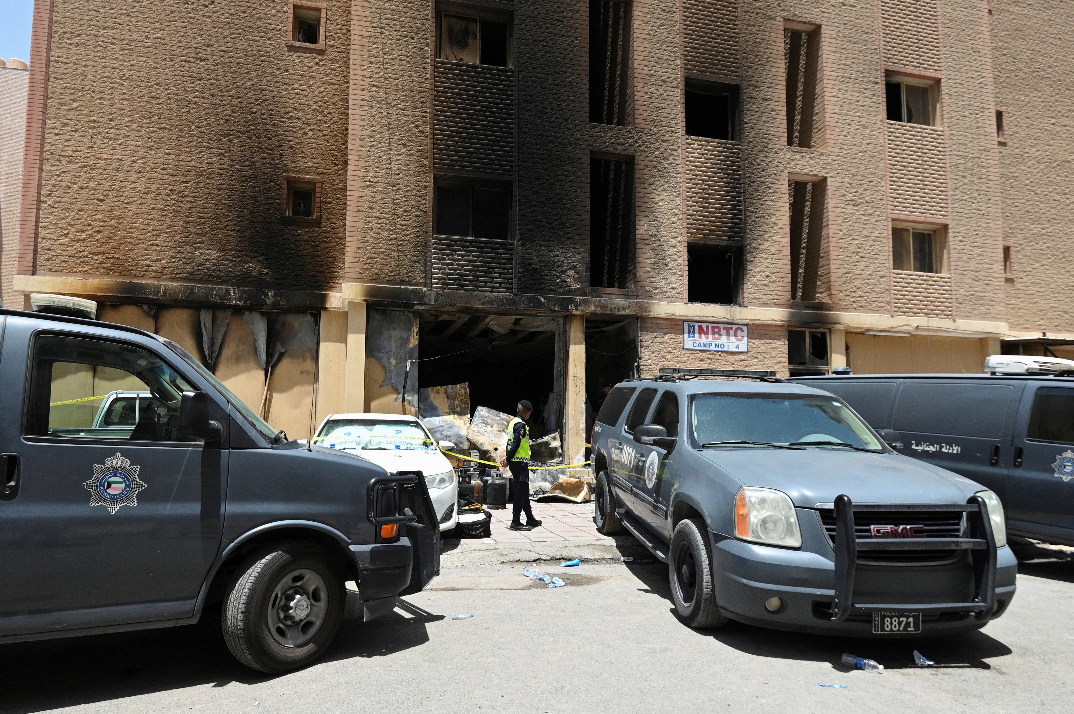 Un agente de policía kuwaití frente al edificio incendiado en Mangaf (REUTERS)