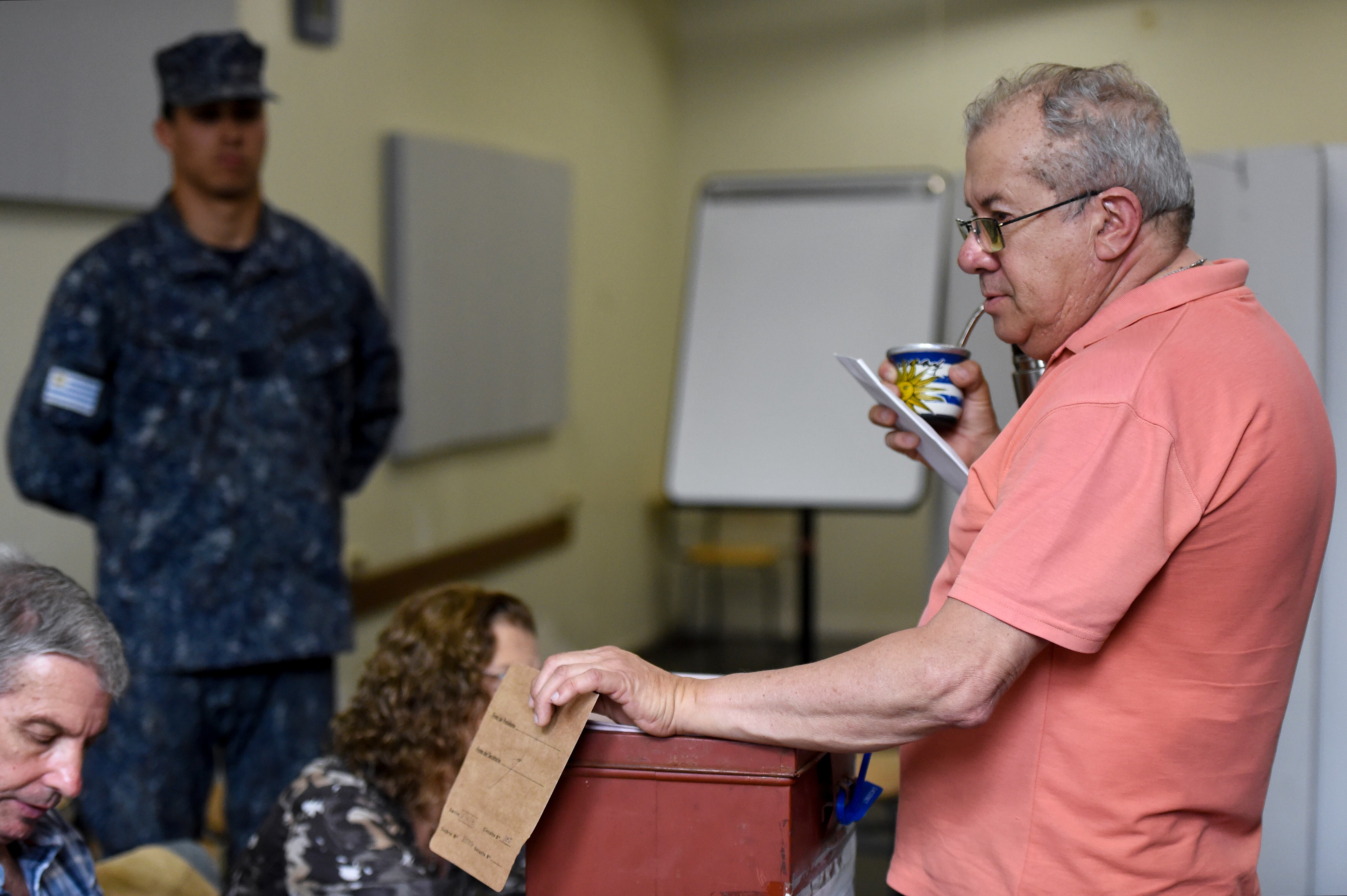 A man holding a mate gourd with a design of the Uruguayan flag votes at a polling station in Montevideo during Uruguay's general election on October 27, 2019. (Photo by Eitan ABRAMOVICH / AFP)